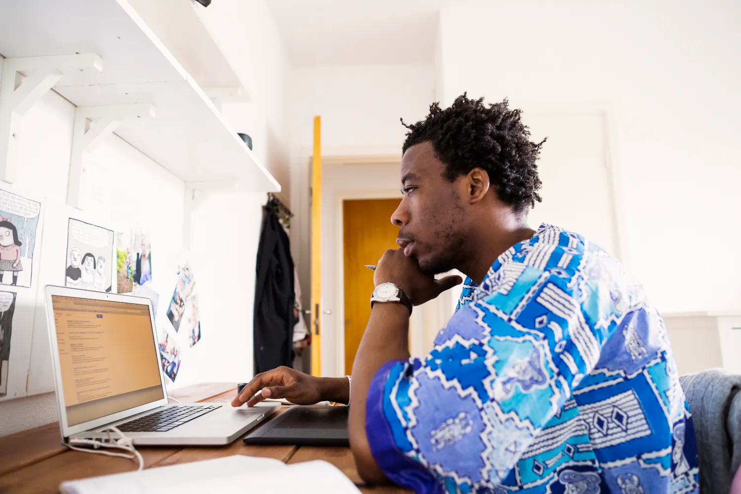 Homme habillé en bleu en train de travaille sur un ordinateur portable dans un bureau.