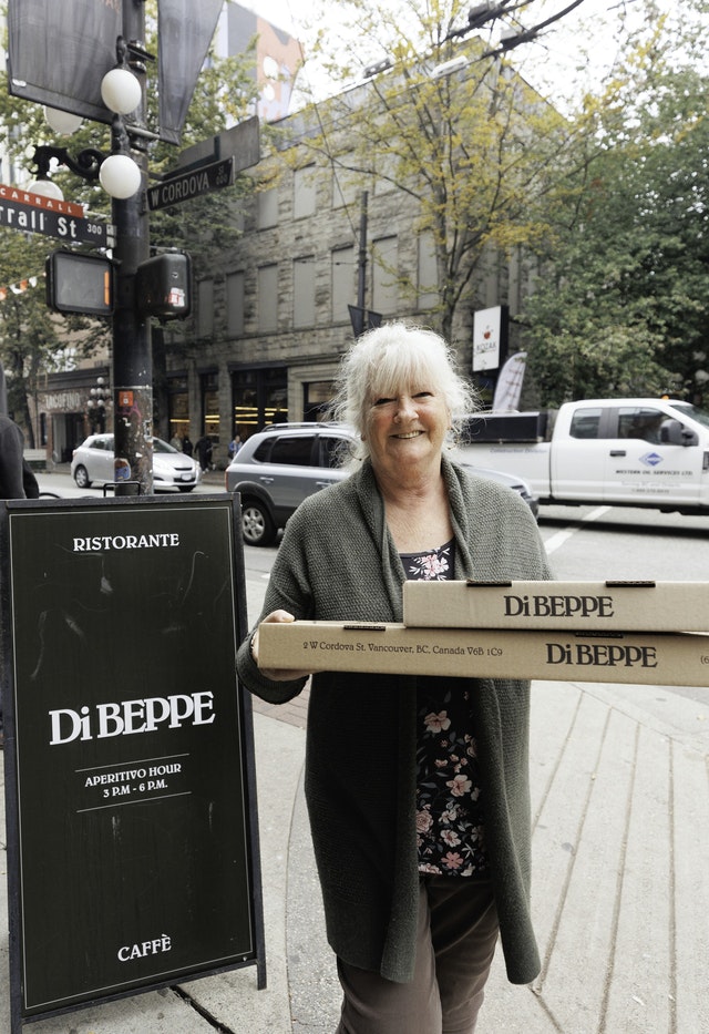 A resident leaving Di Beppe Café with two large pizzas