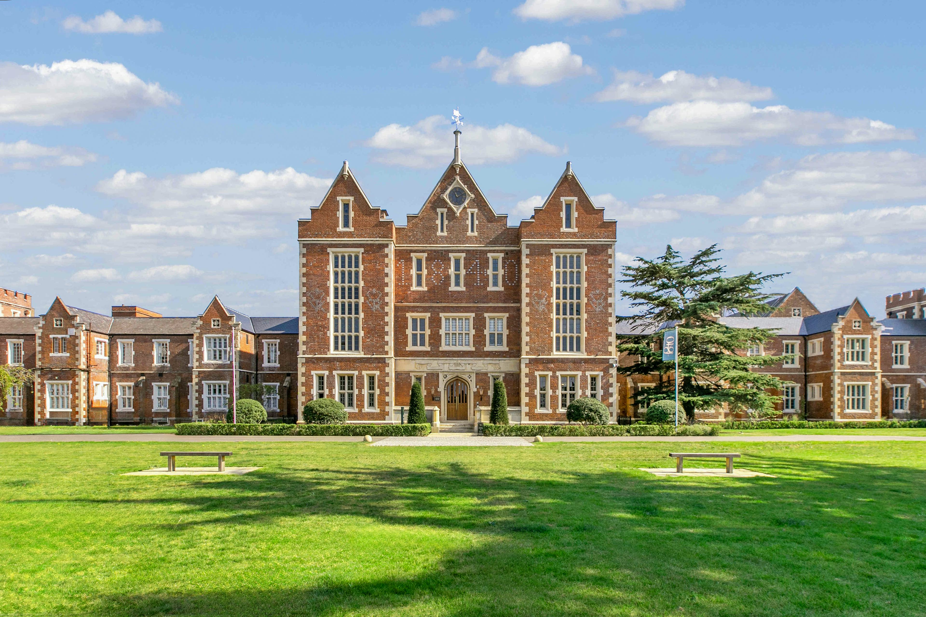 Caption: a large brick building sitting on top of a lush green field