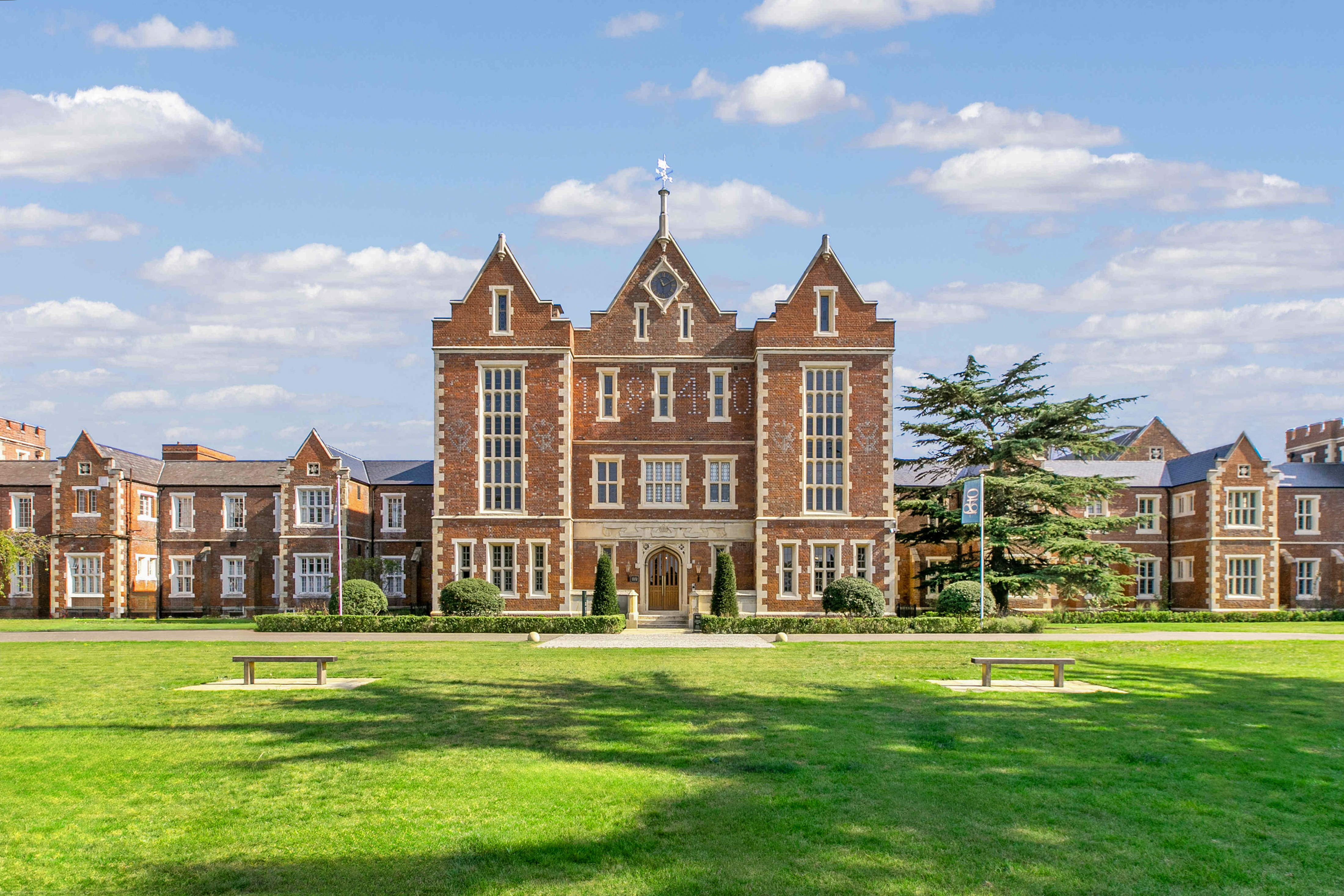 Caption: a large brick building sitting on top of a lush green field