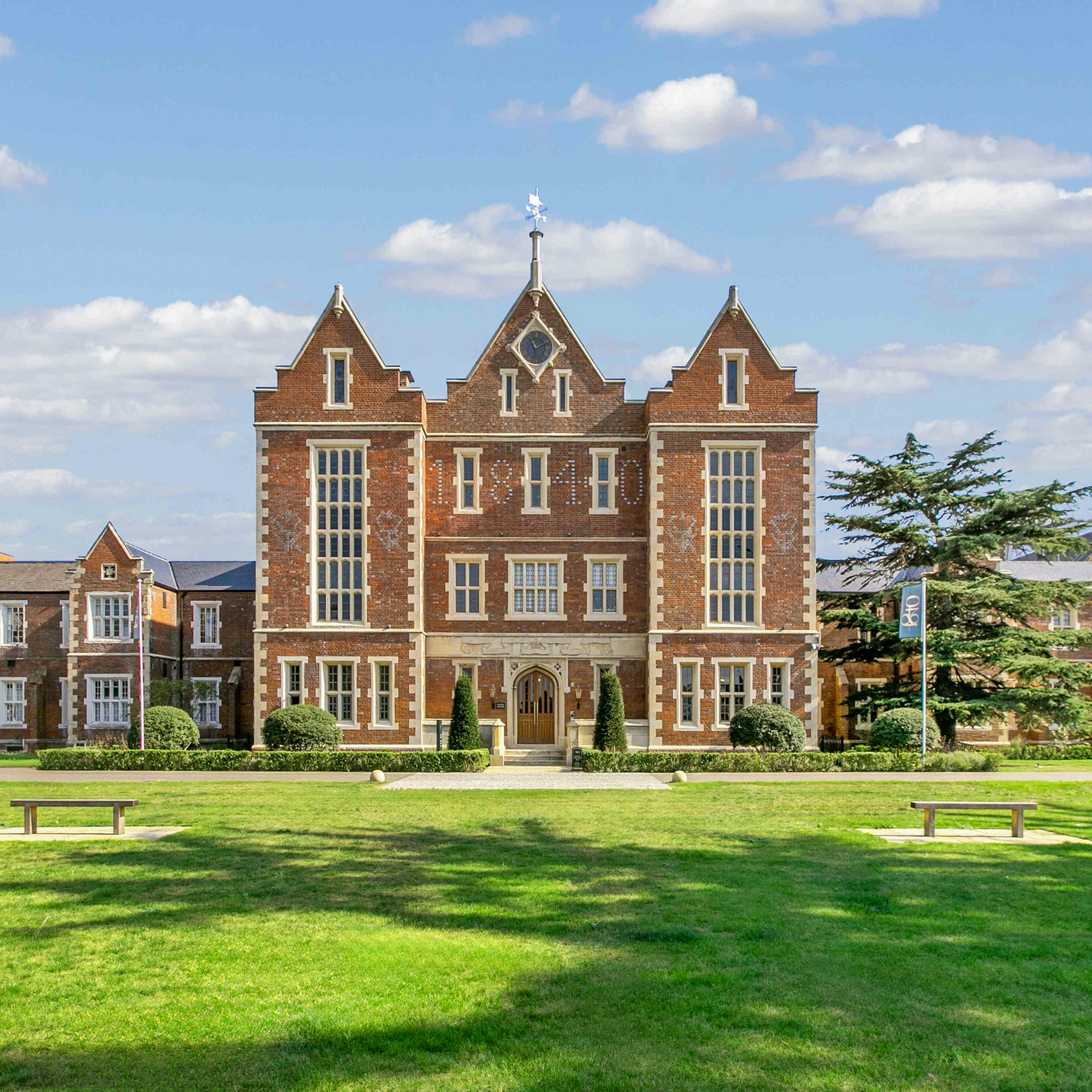 Caption: a large brick building sitting on top of a lush green field