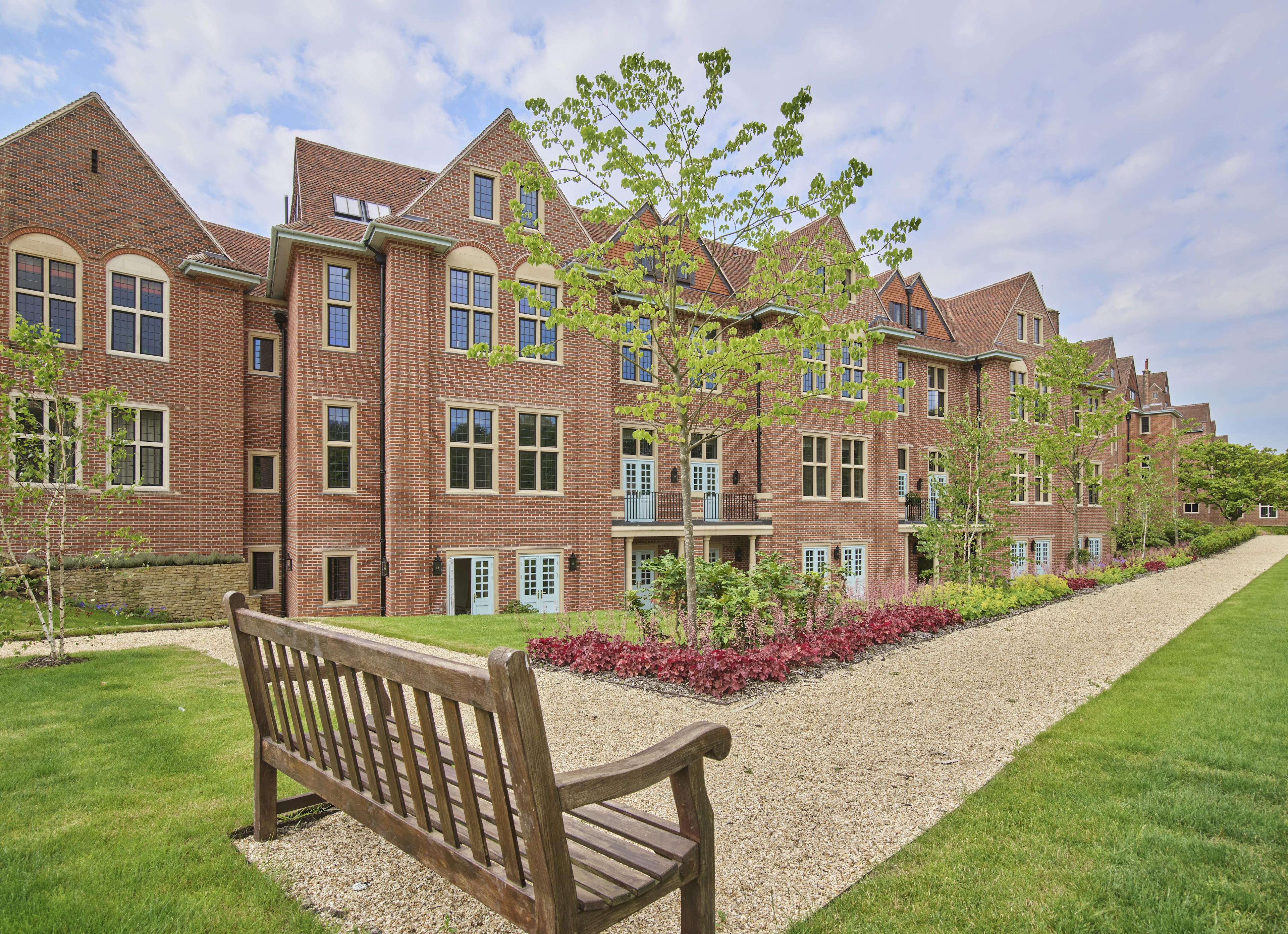 Caption: a wooden bench sitting in front of a brick building
