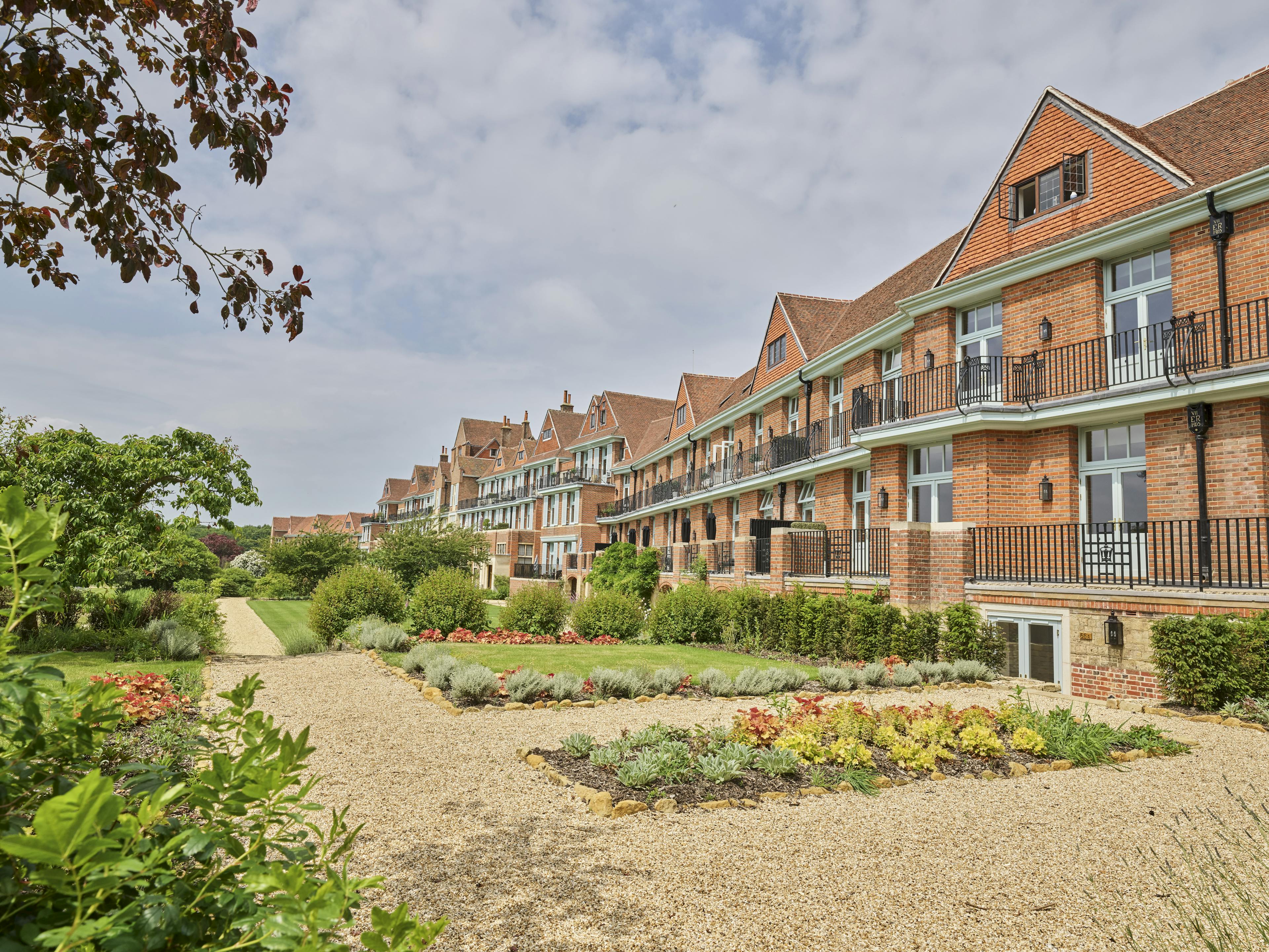 Caption: a row of brick apartment buildings next to a garden