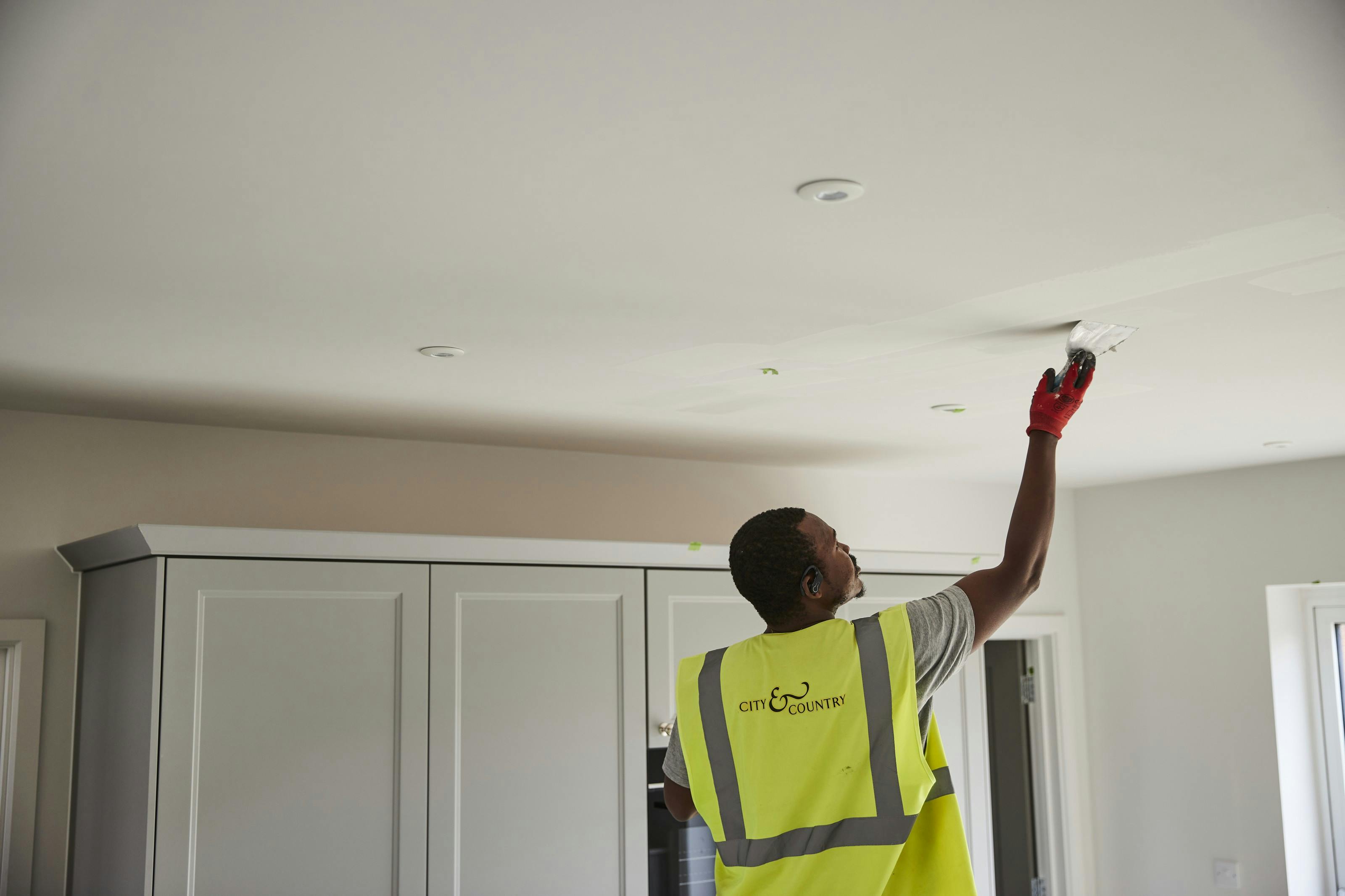 A workman filling crack in a ceiling
