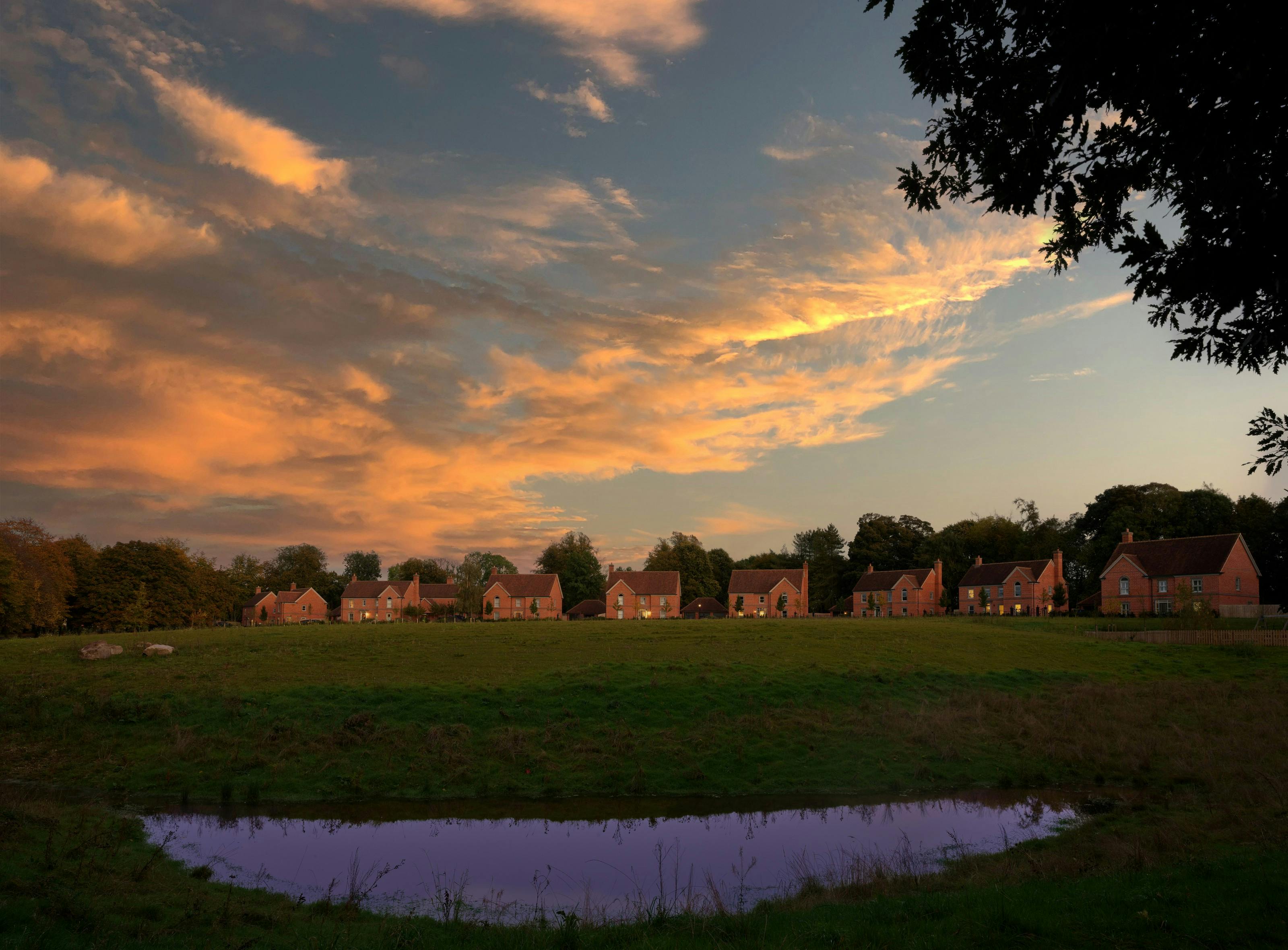 A street scene of a row of houses across a lake at dusk