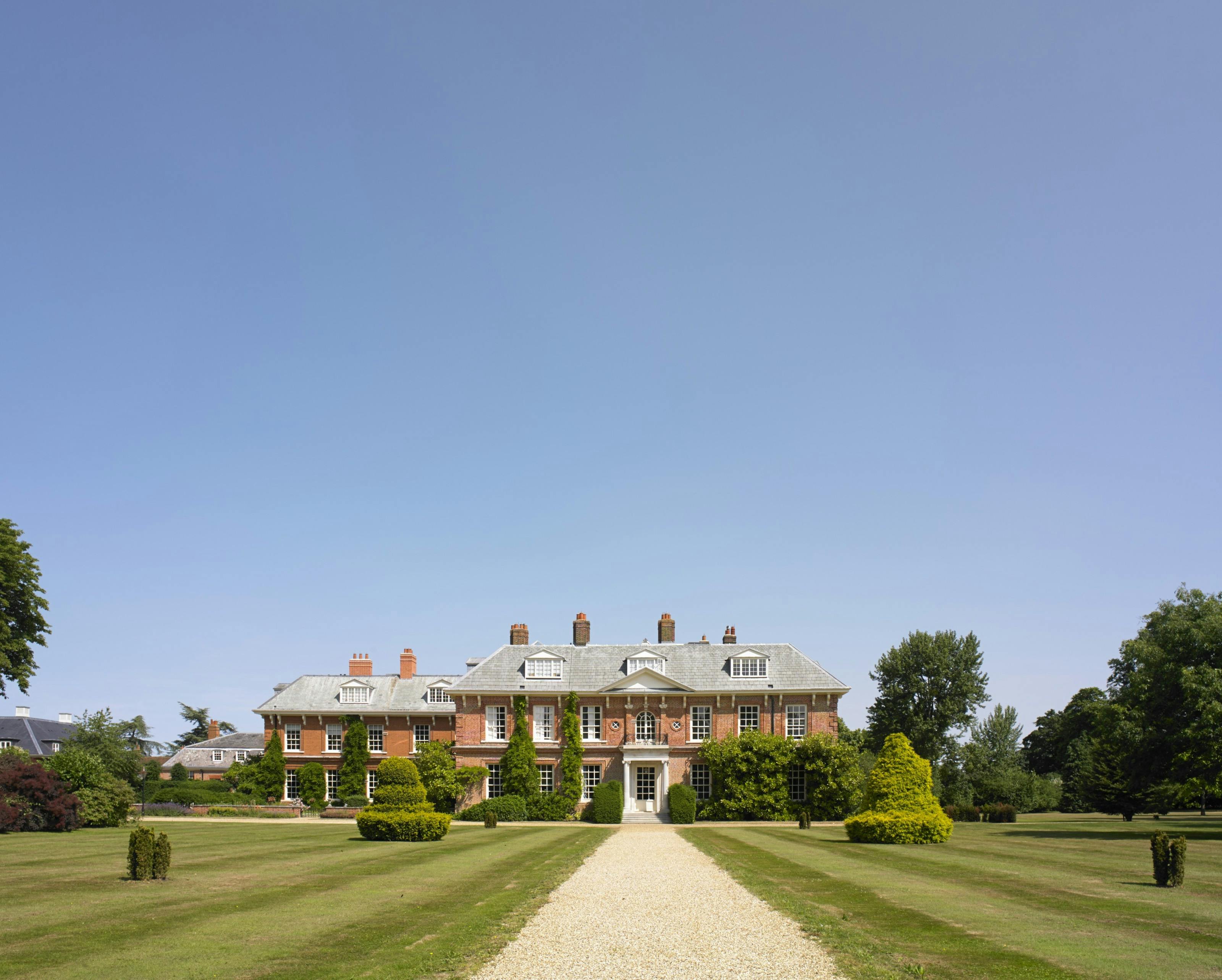 A drive leading up to a large red brick mansion house in the background