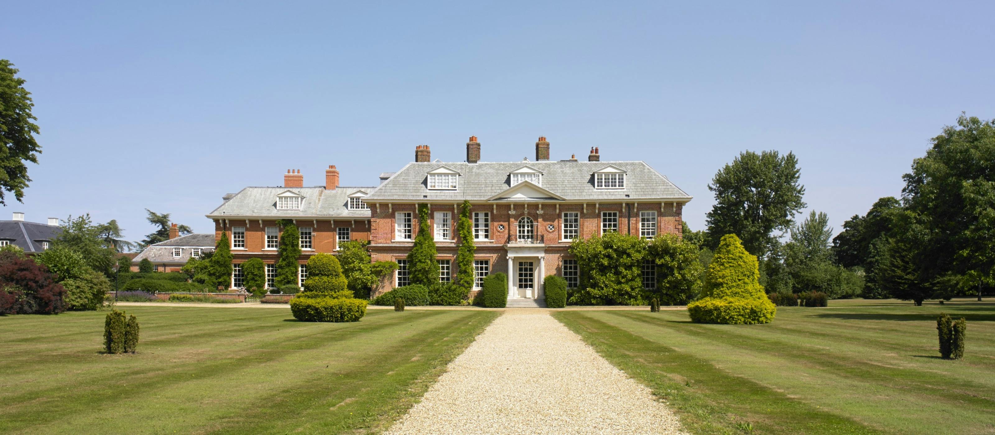 A drive leading up to a large red brick mansion house in the background