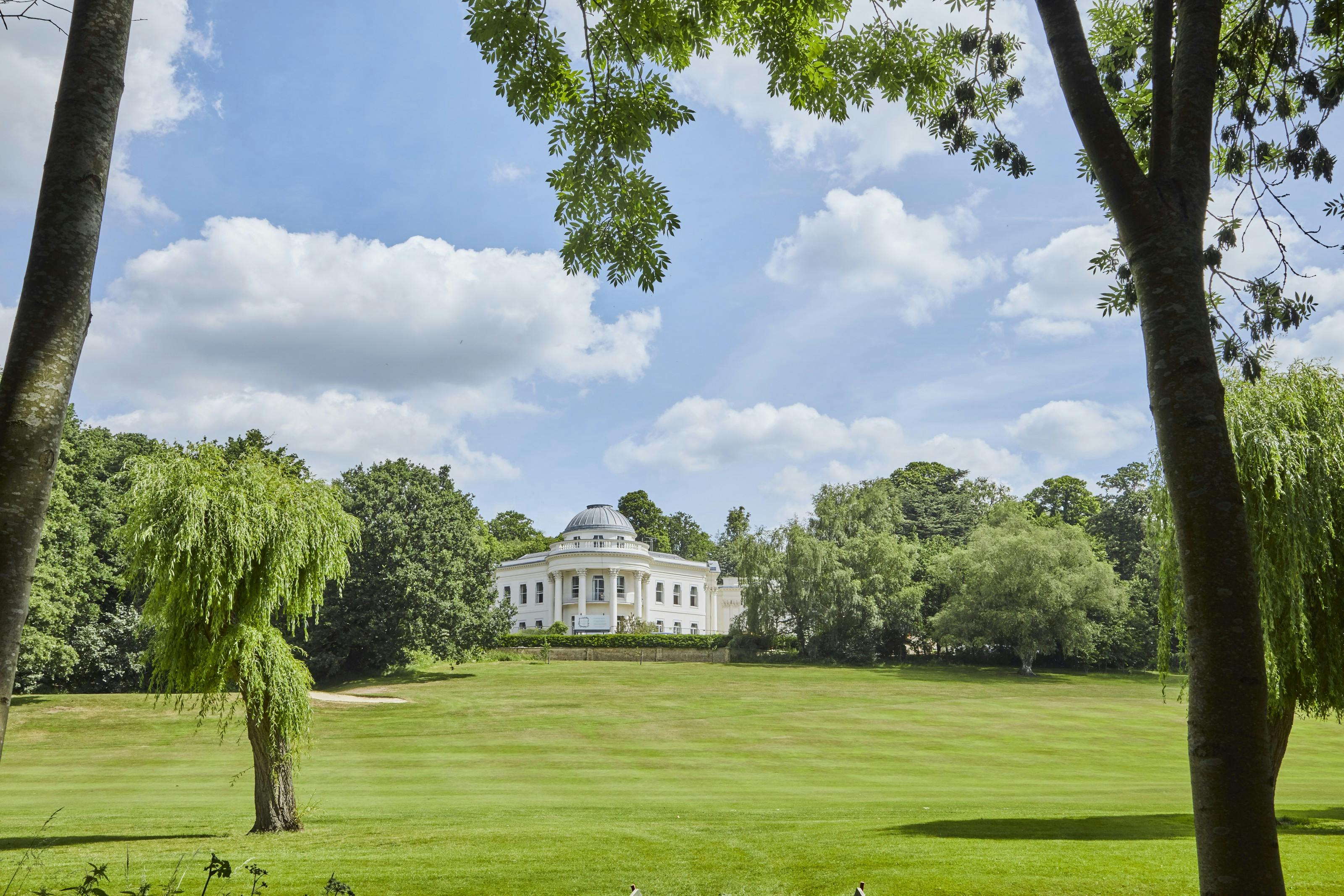 Caption: a large white house in the middle of a lush green field
