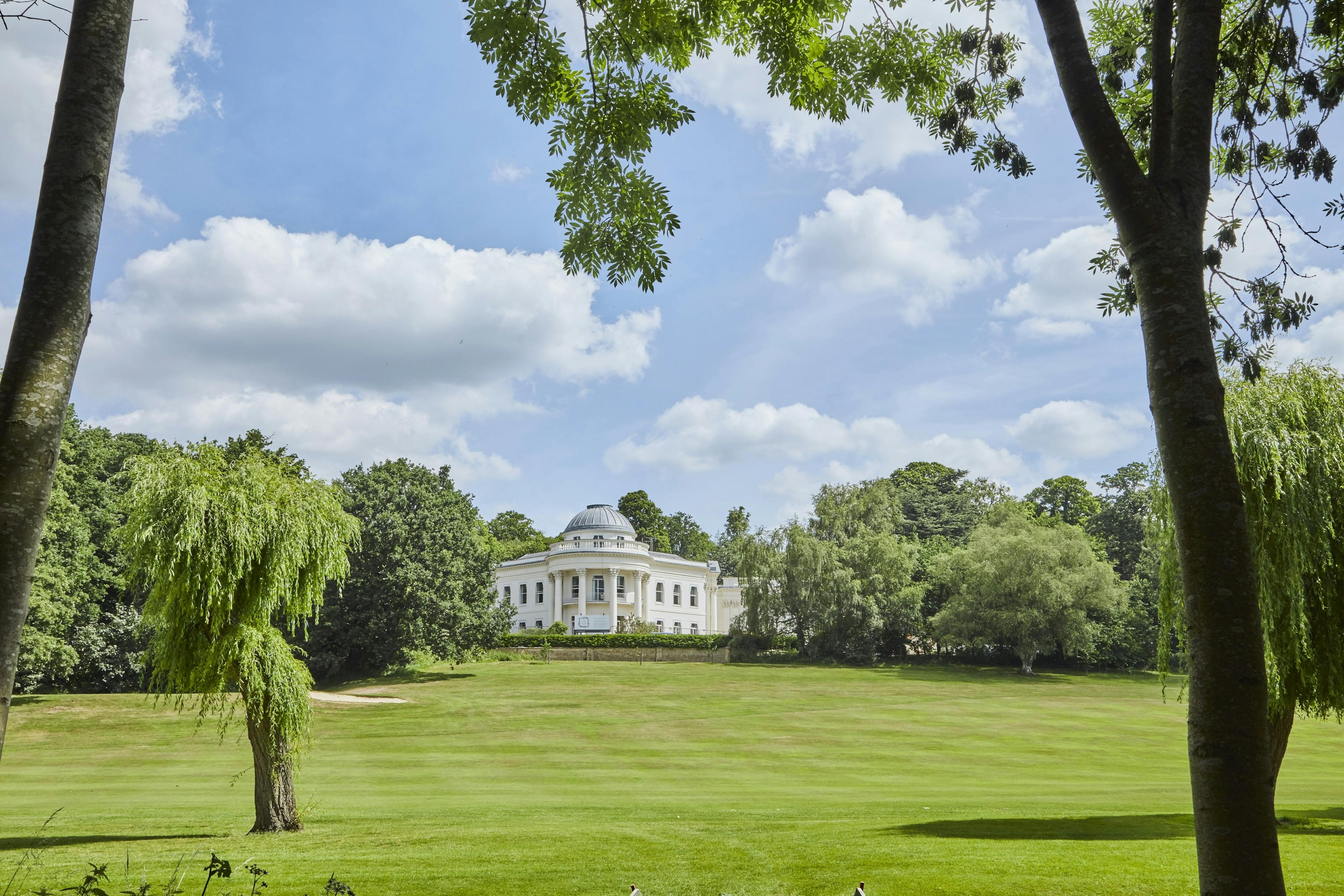 Caption: a large white house in the middle of a lush green field