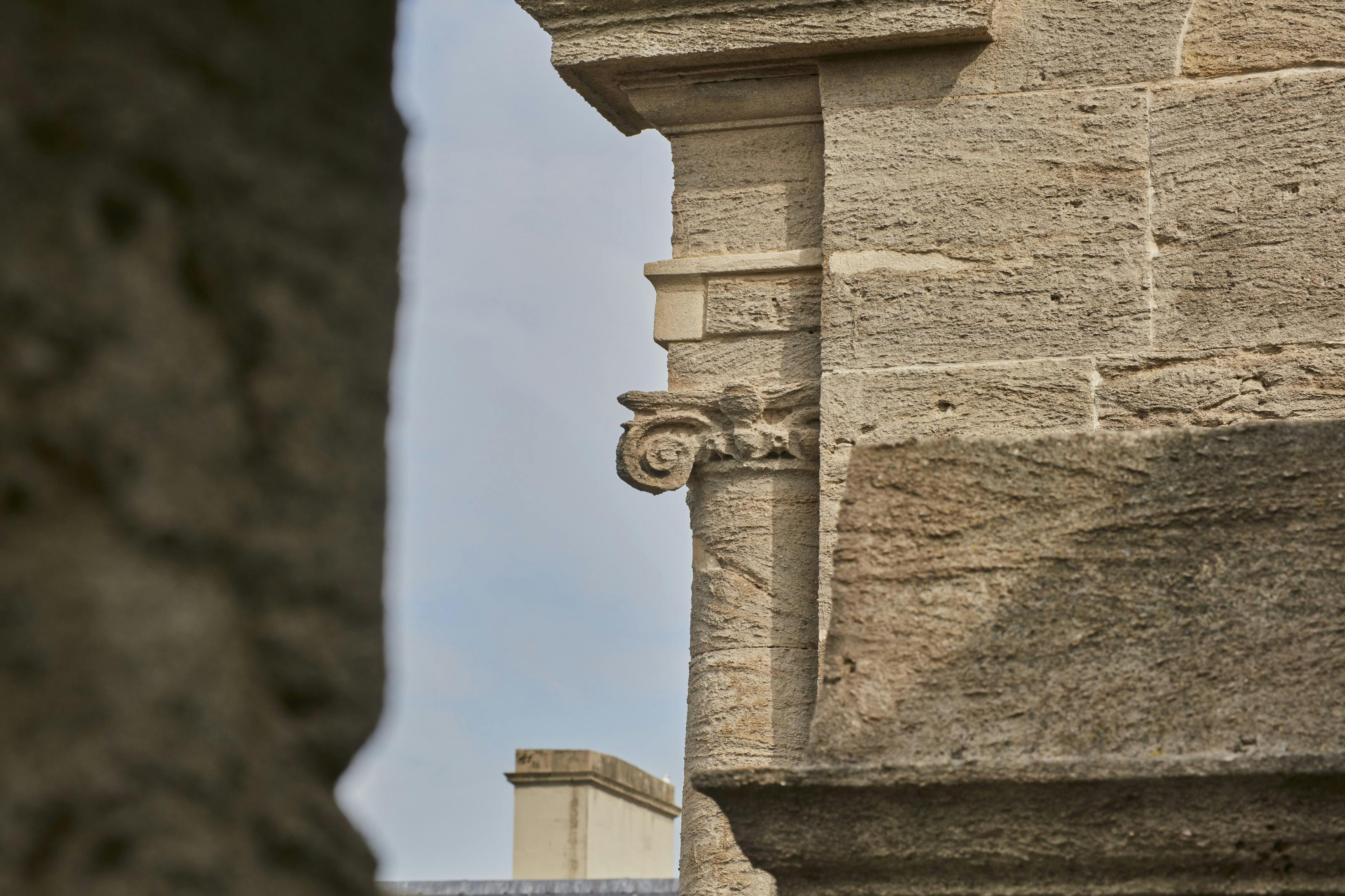 Caption: a stone building with a clock tower in the background