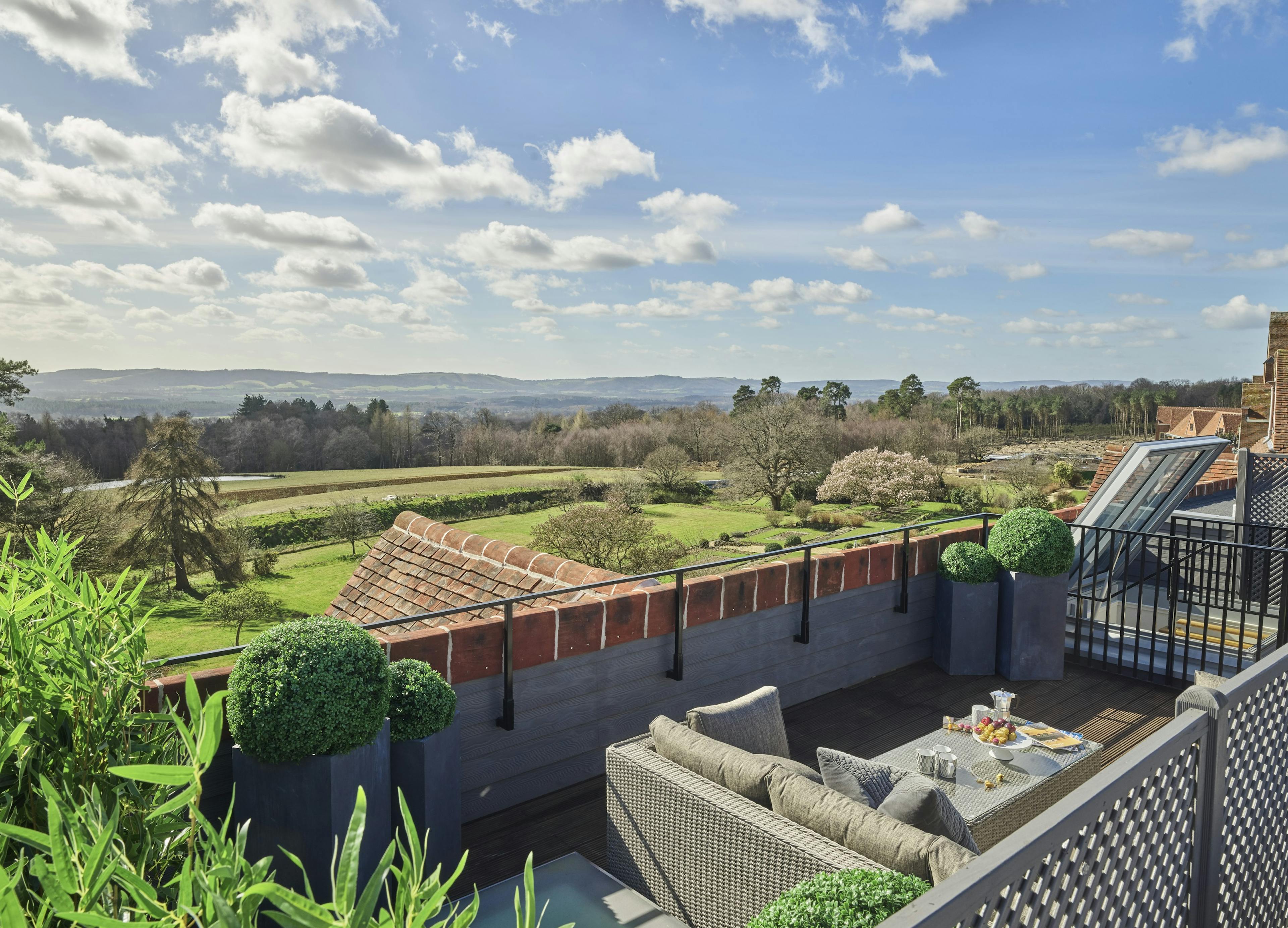 Caption: a balcony with a table and chairs and a view of the countryside