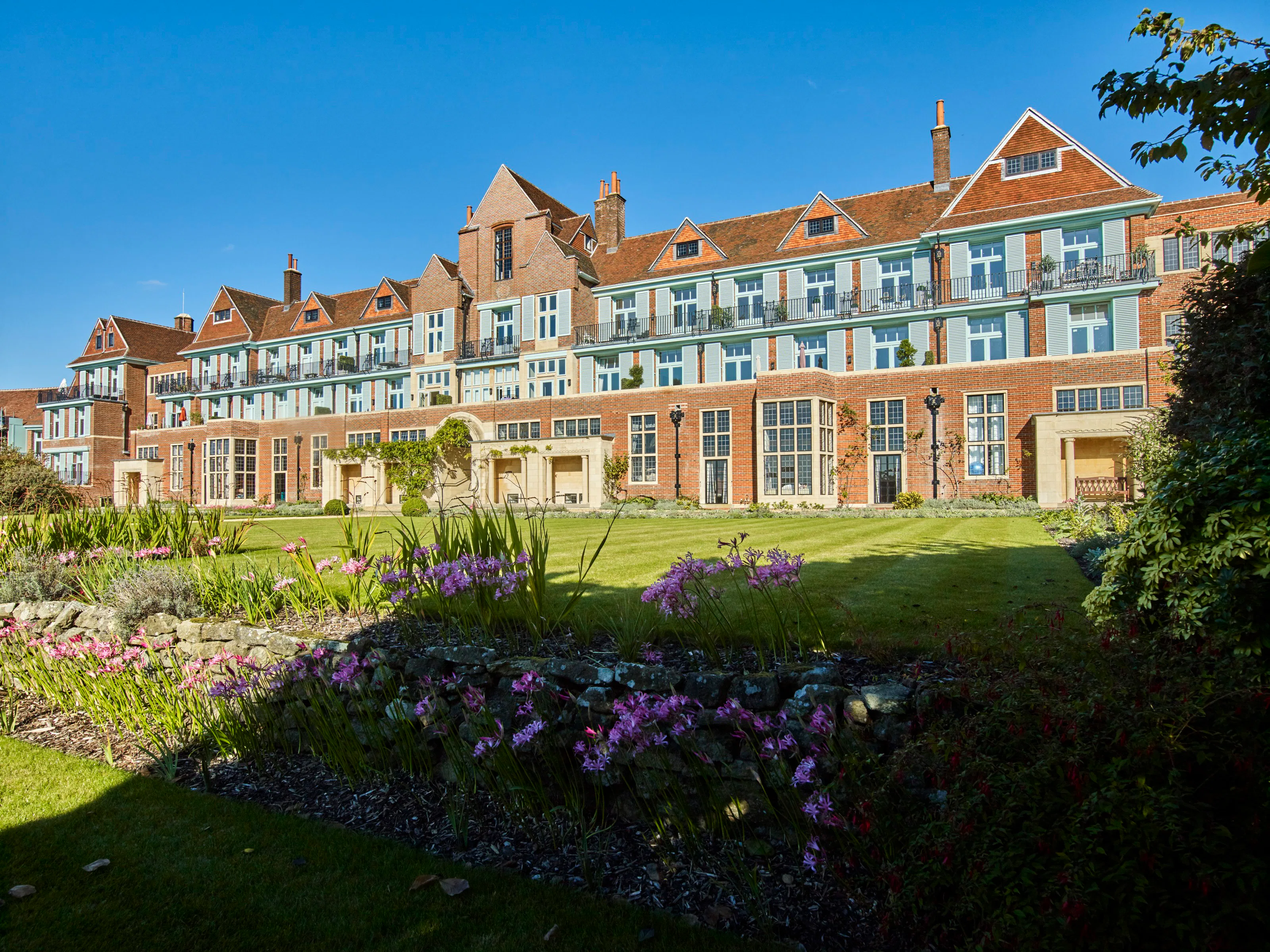 Caption: a large building with many windows and a lawn in front of it