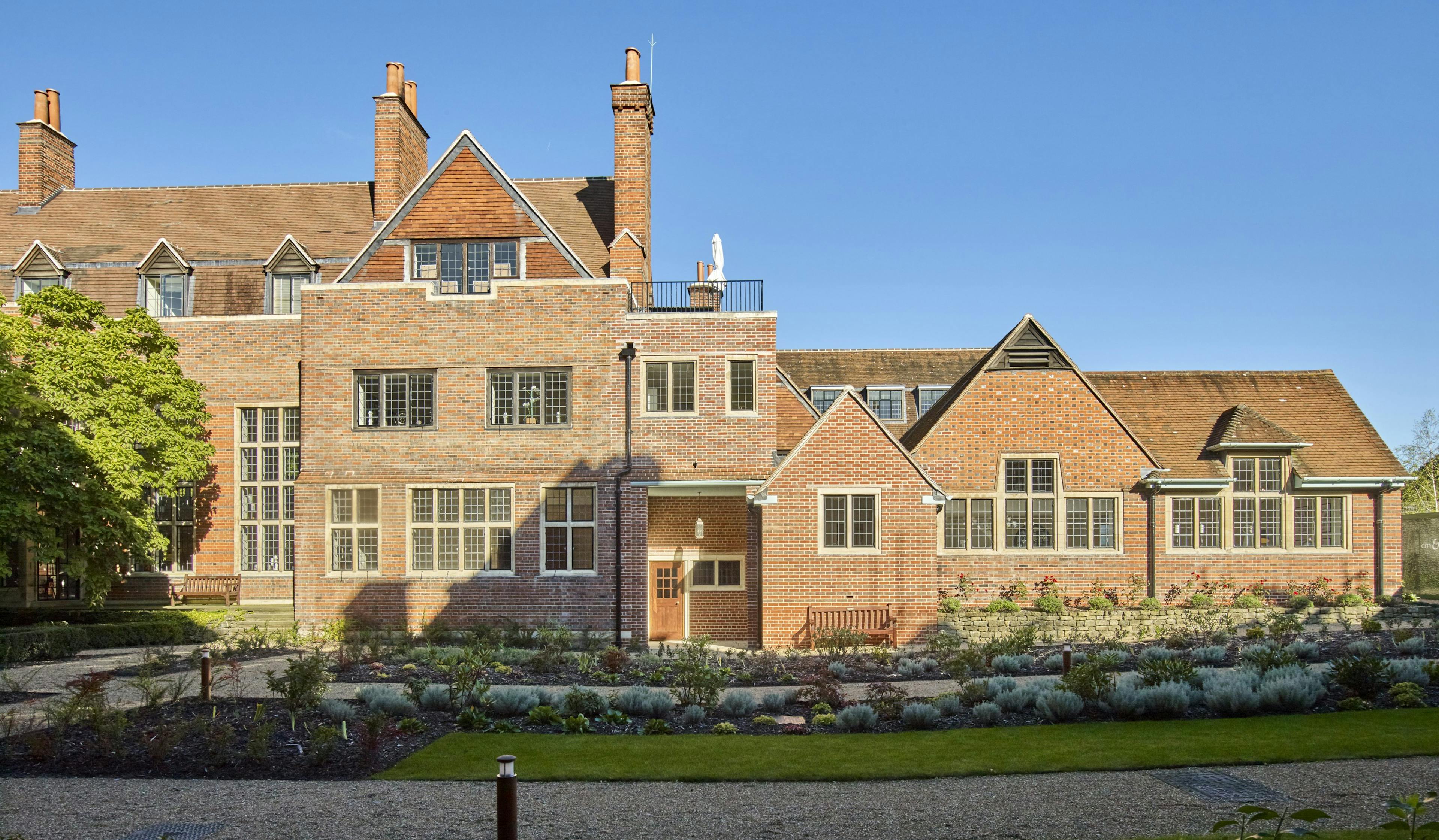 Caption: a large brick building with a garden in front of it