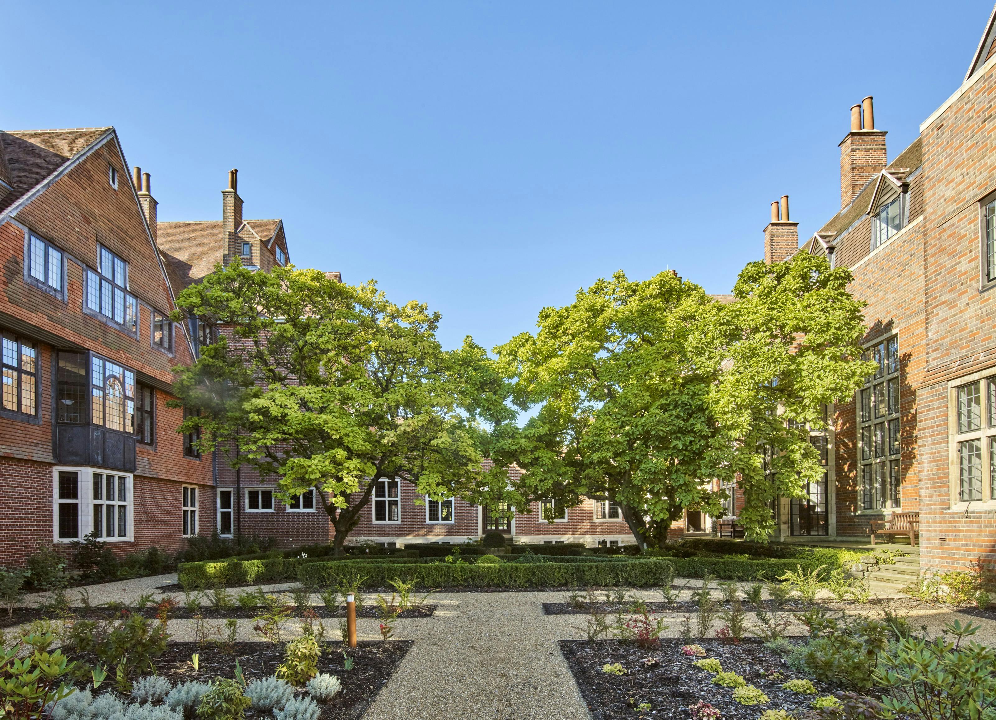 Caption: a garden in front of a brick building