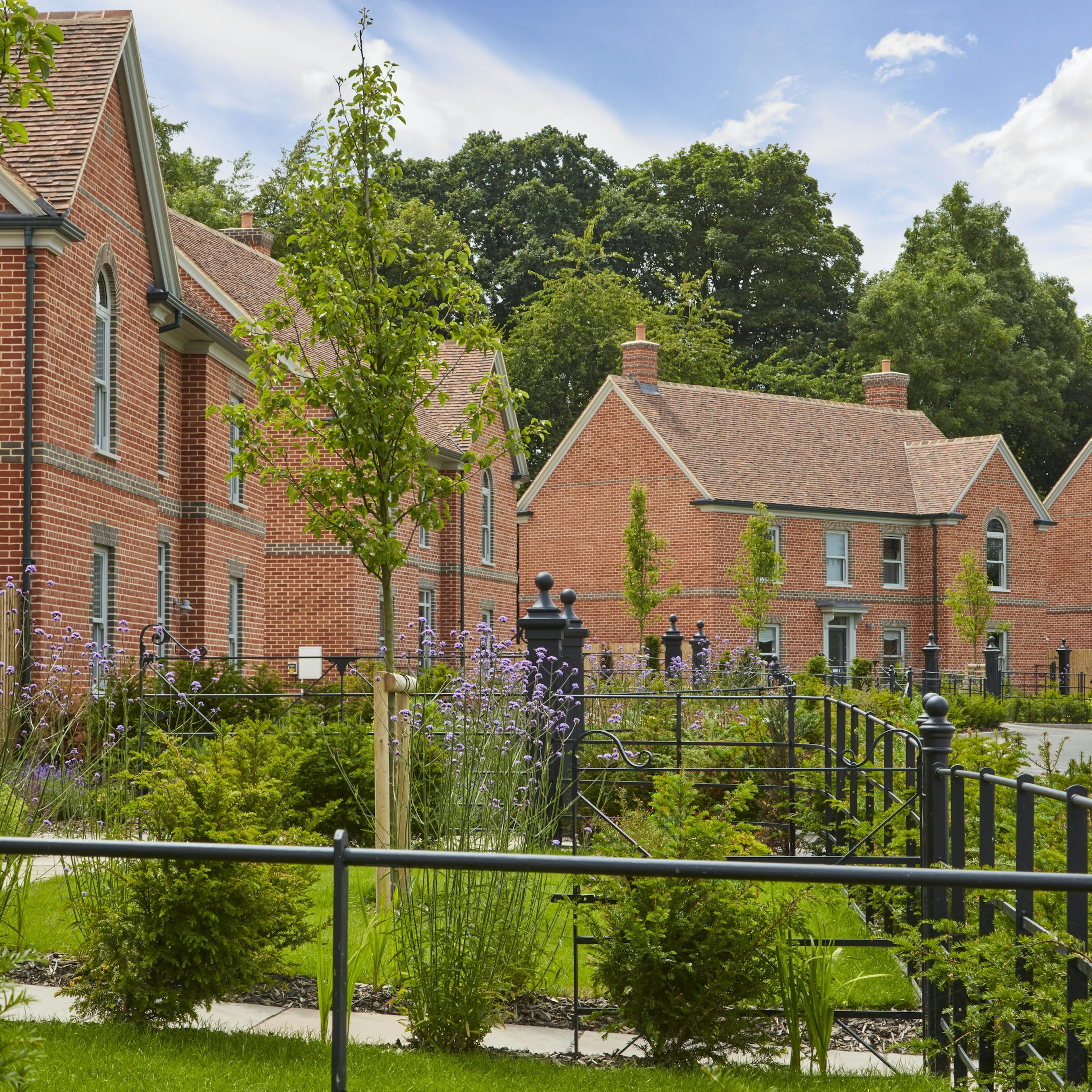 Caption: a large brick building with a garden in front of it