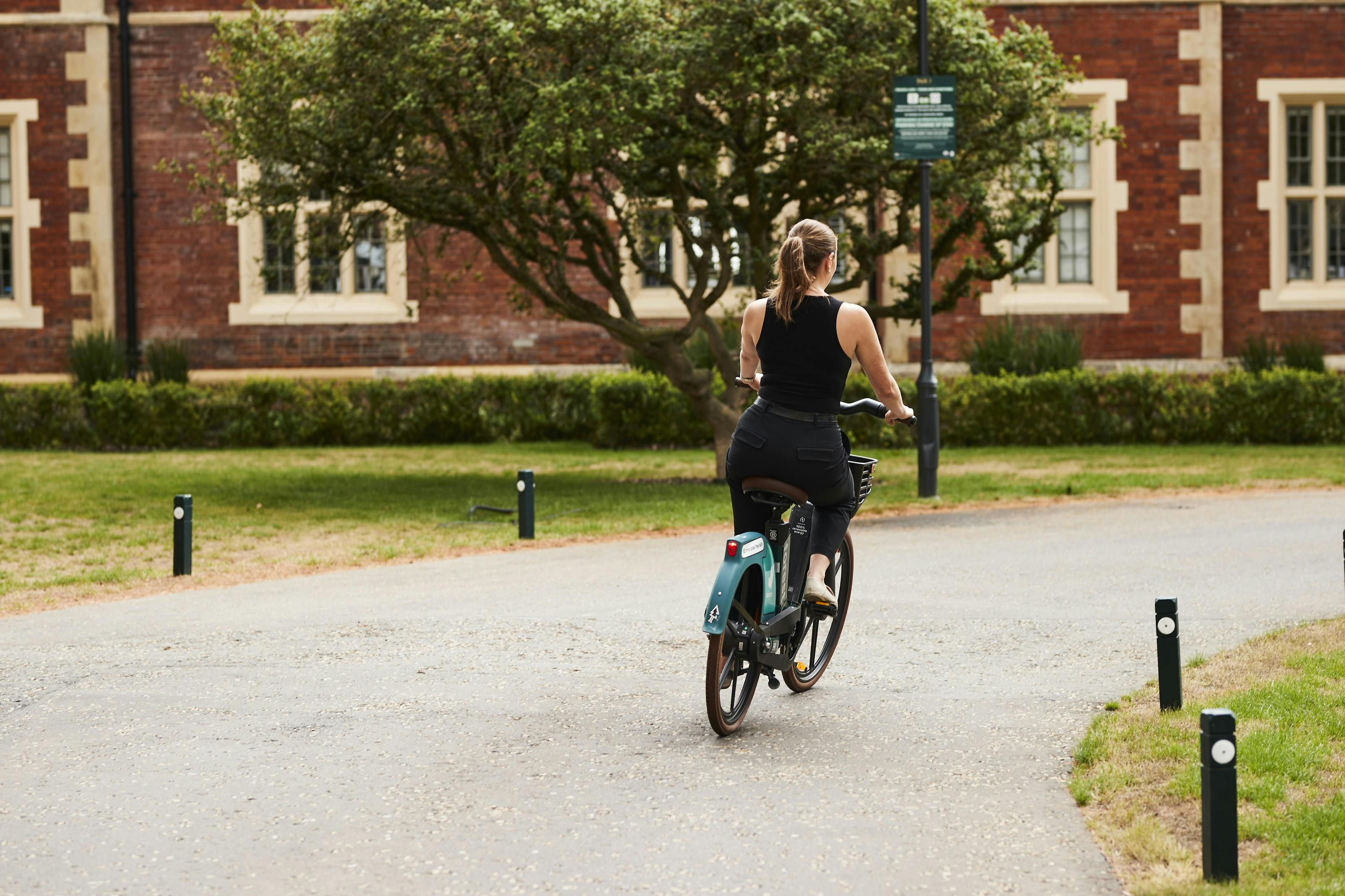 A lady on a bicycle riding through a park