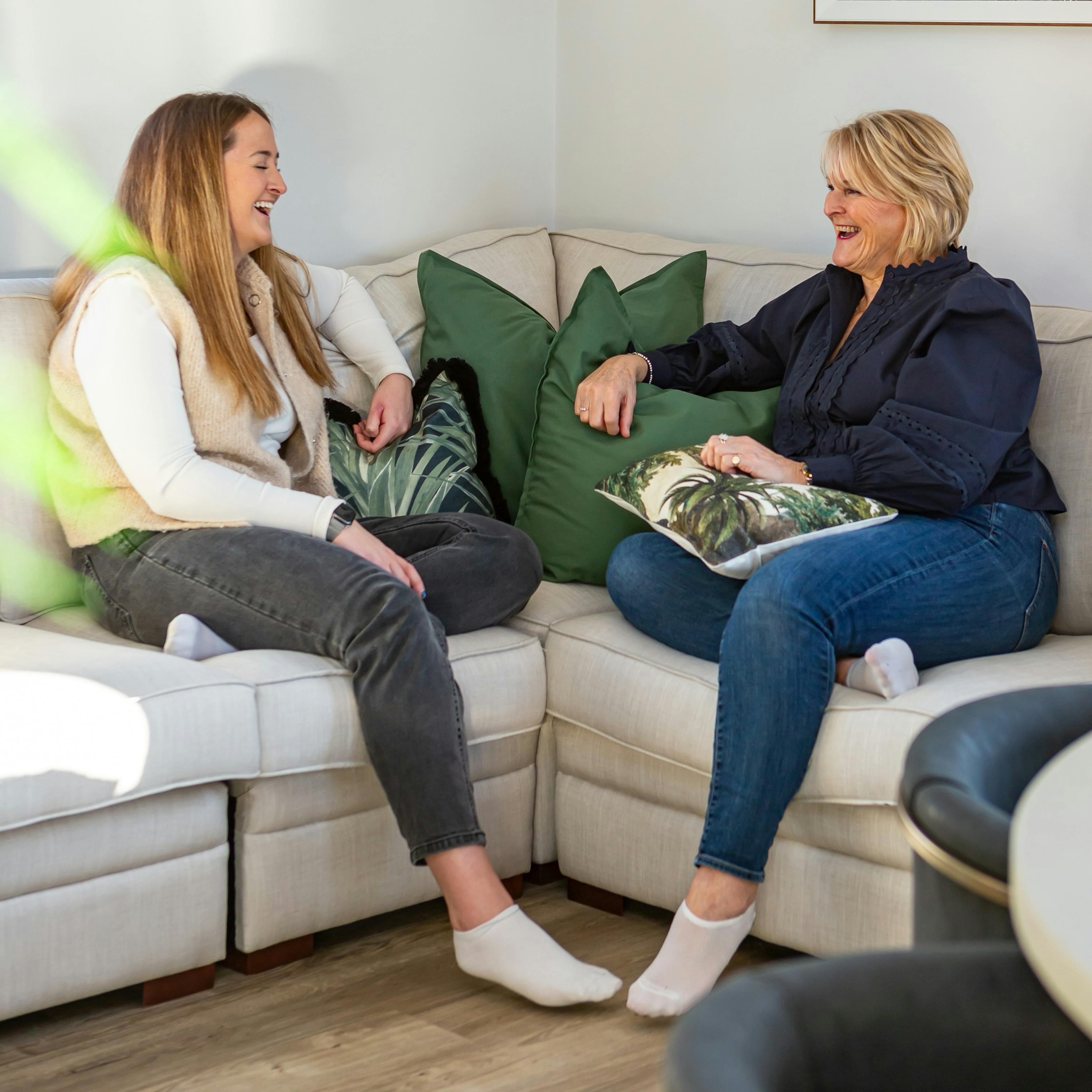 A mother and daughter laughing together on a sofa