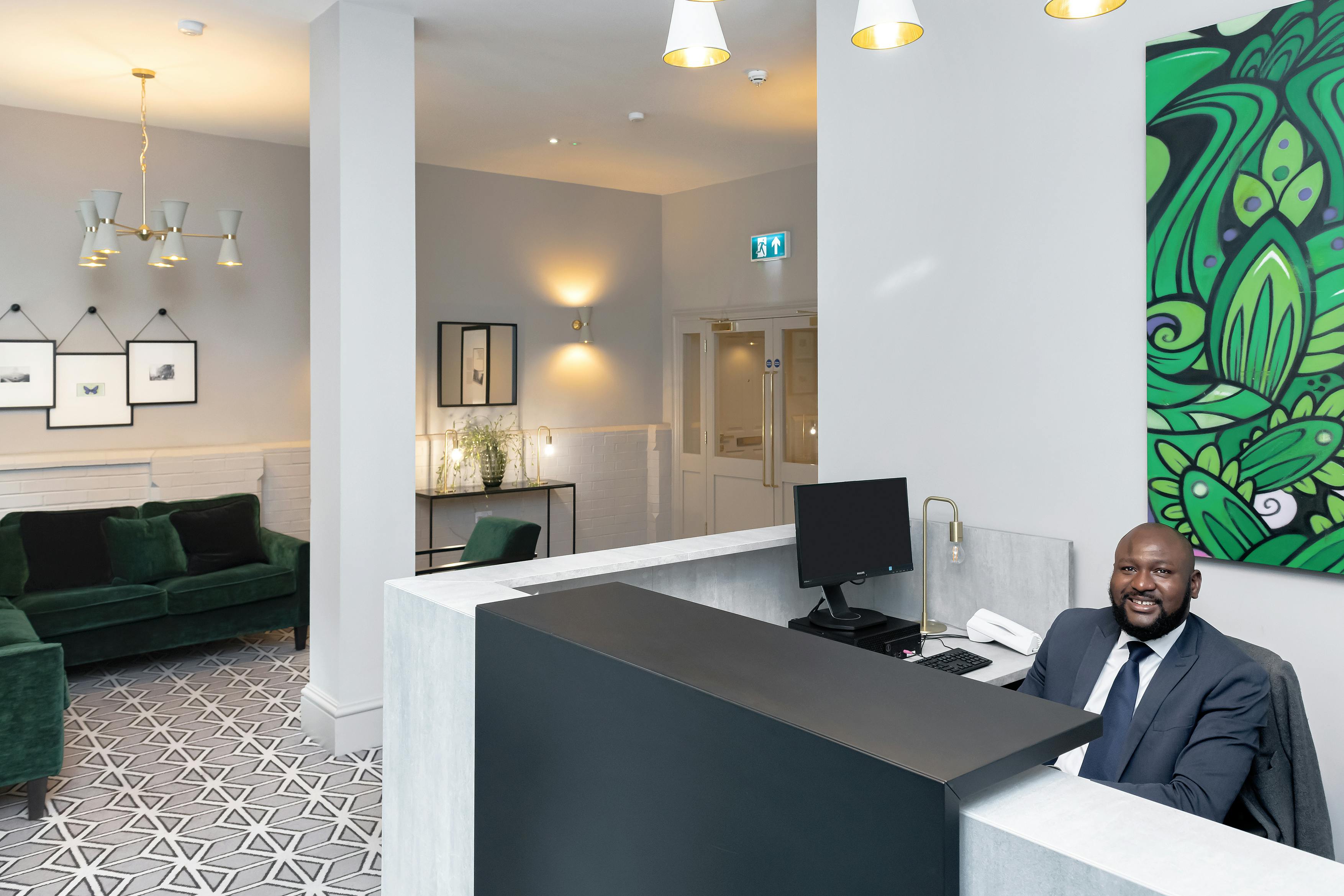 Caption: a man in a suit sitting at a reception desk