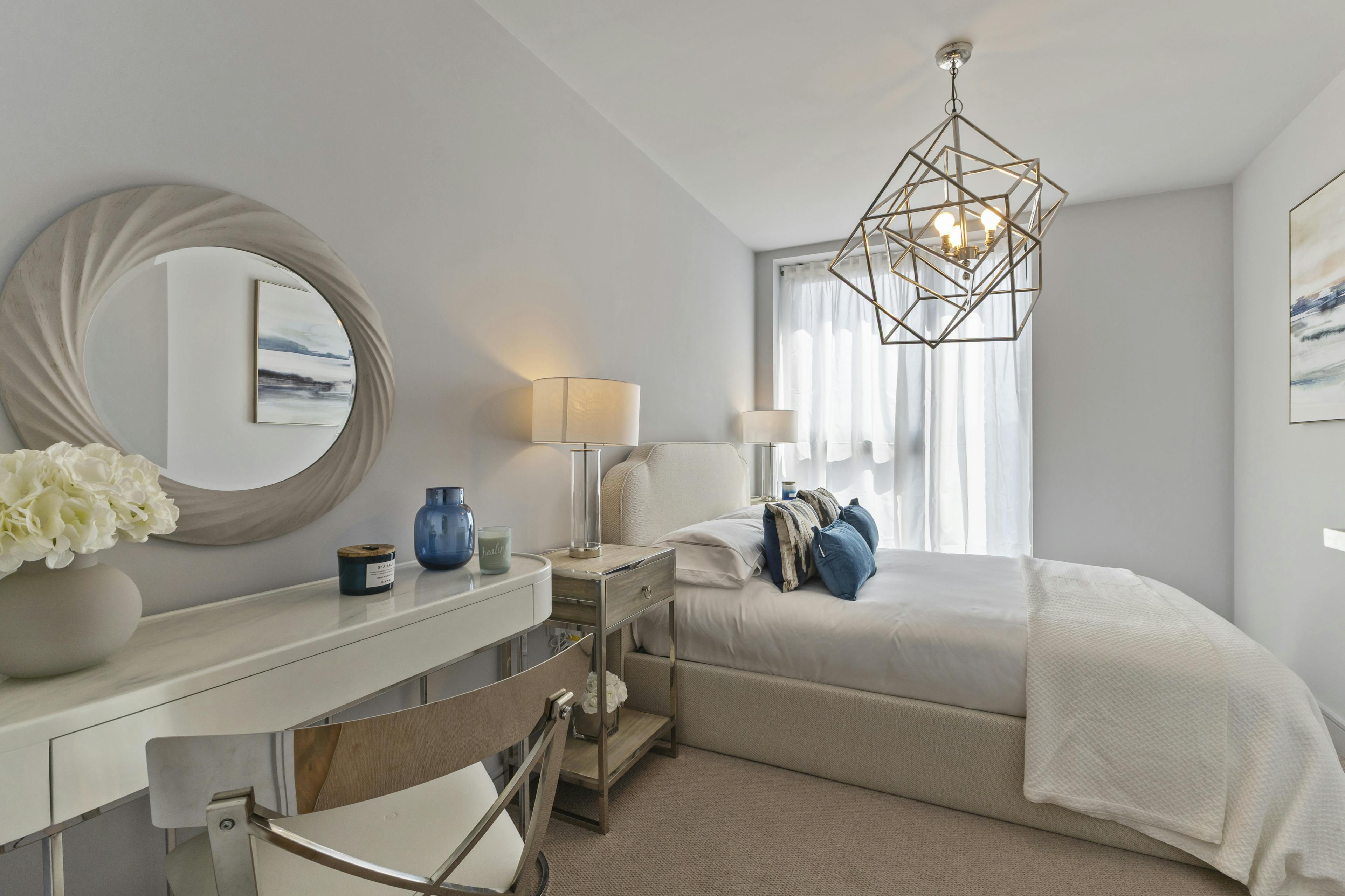 Caption: a bedroom with a bed, desk and mirror