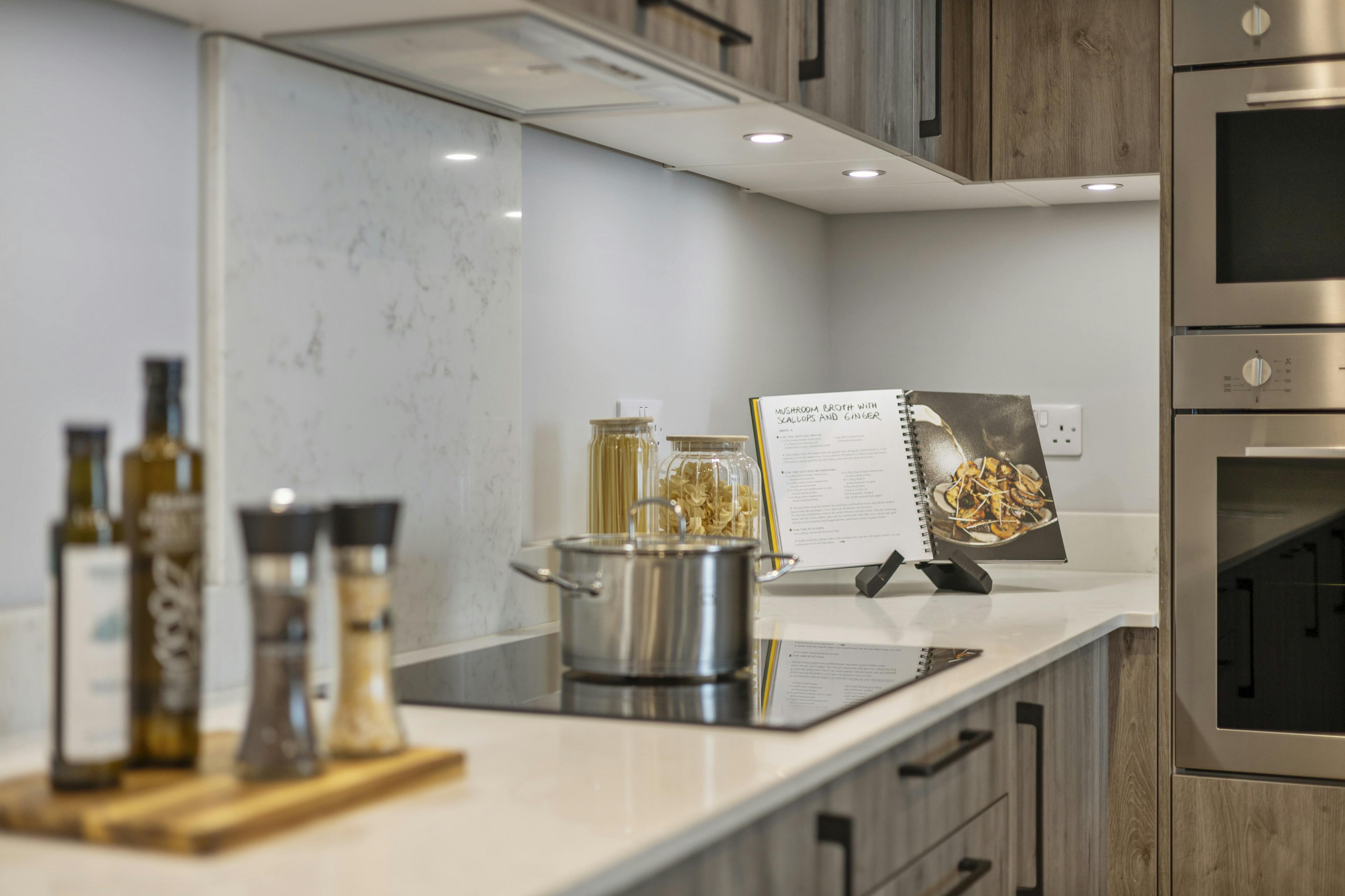 Caption: a kitchen counter with a cookbook and wine bottles on it