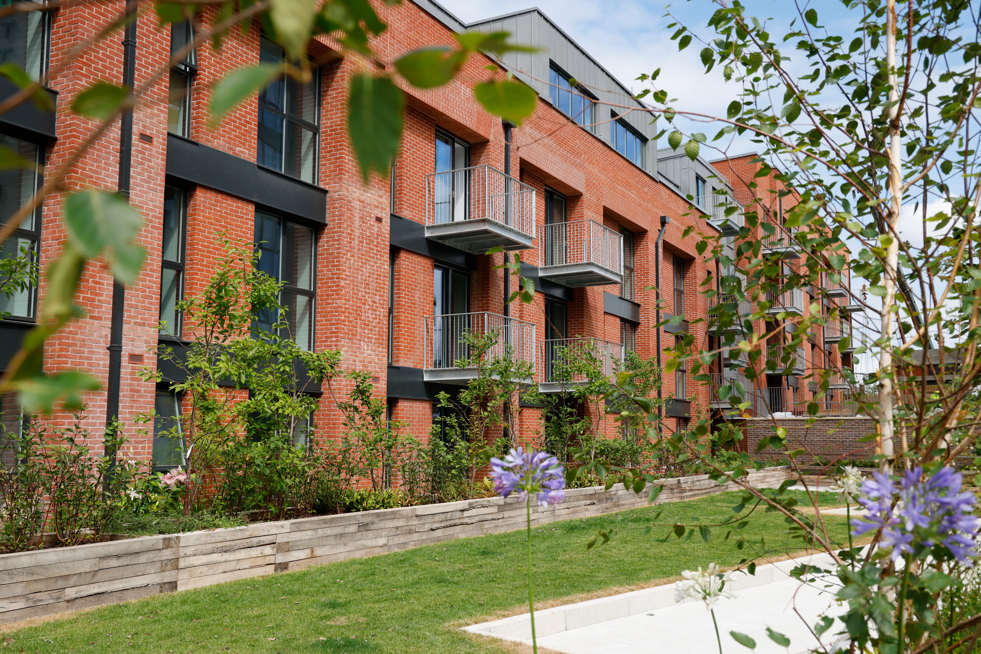Caption: a row of brick apartment buildings next to a lush green park
