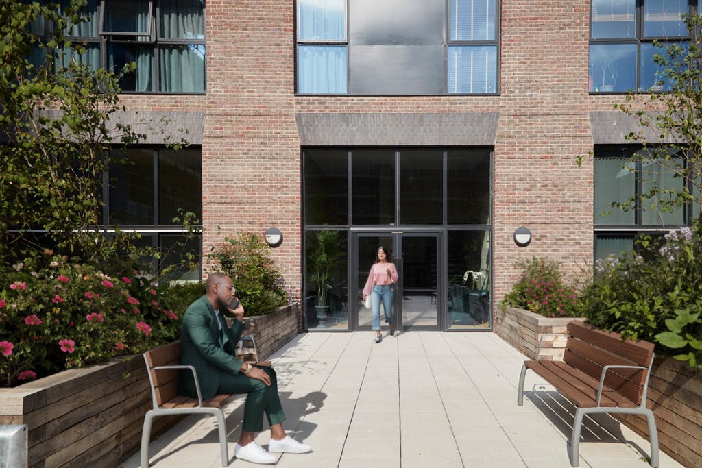 Caption: a man sitting on a bench in front of a building