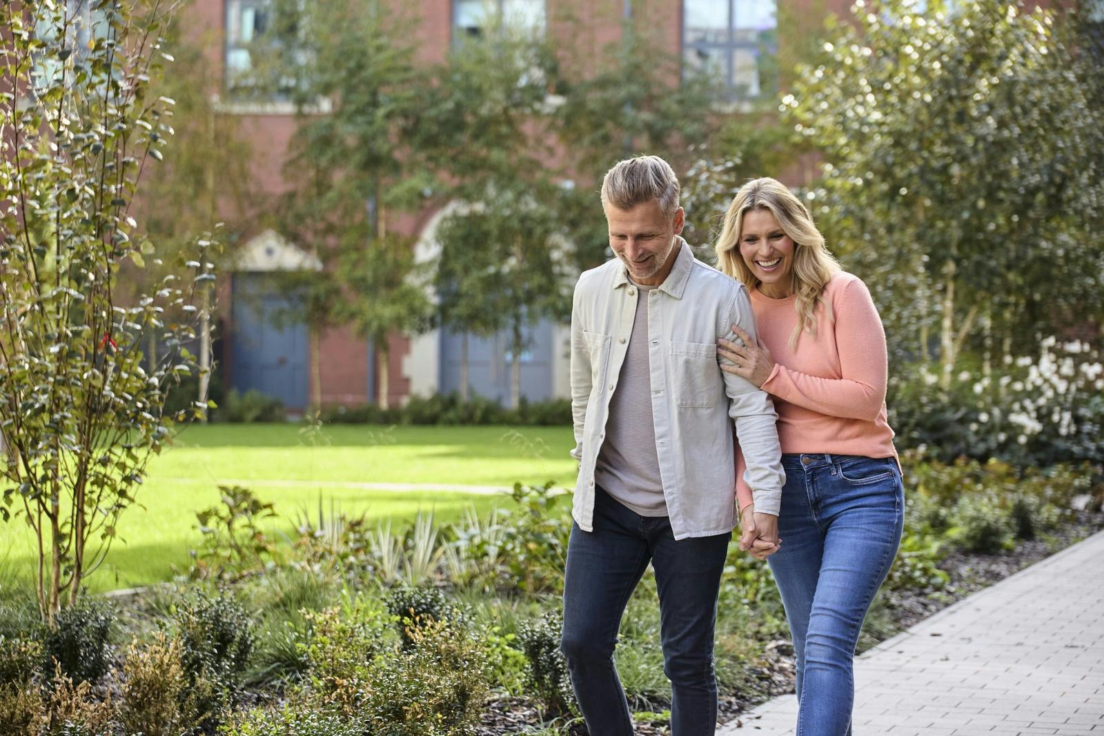 Caption: a man and a woman walking down a sidewalk