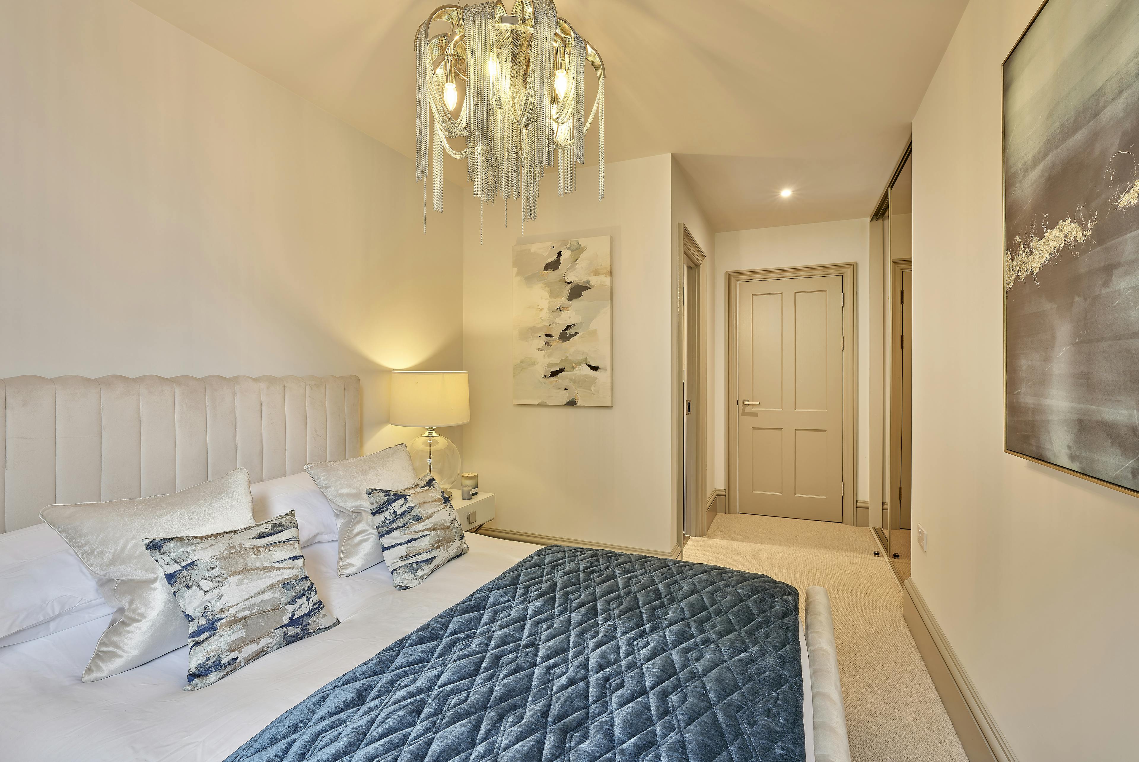 Caption: a bedroom with a chandelier hanging from the ceiling