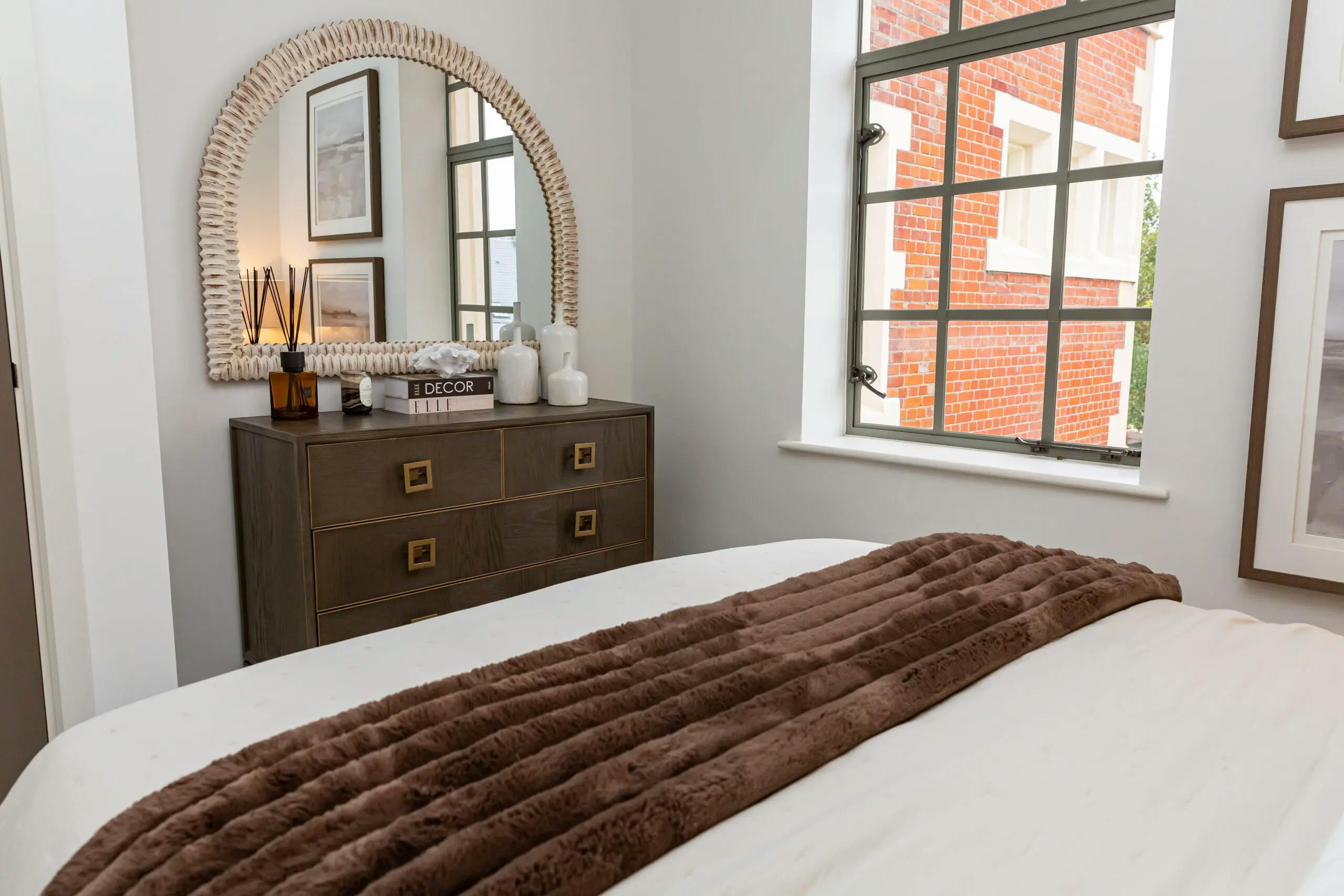 Caption: a bedroom with a bed, dresser and mirror