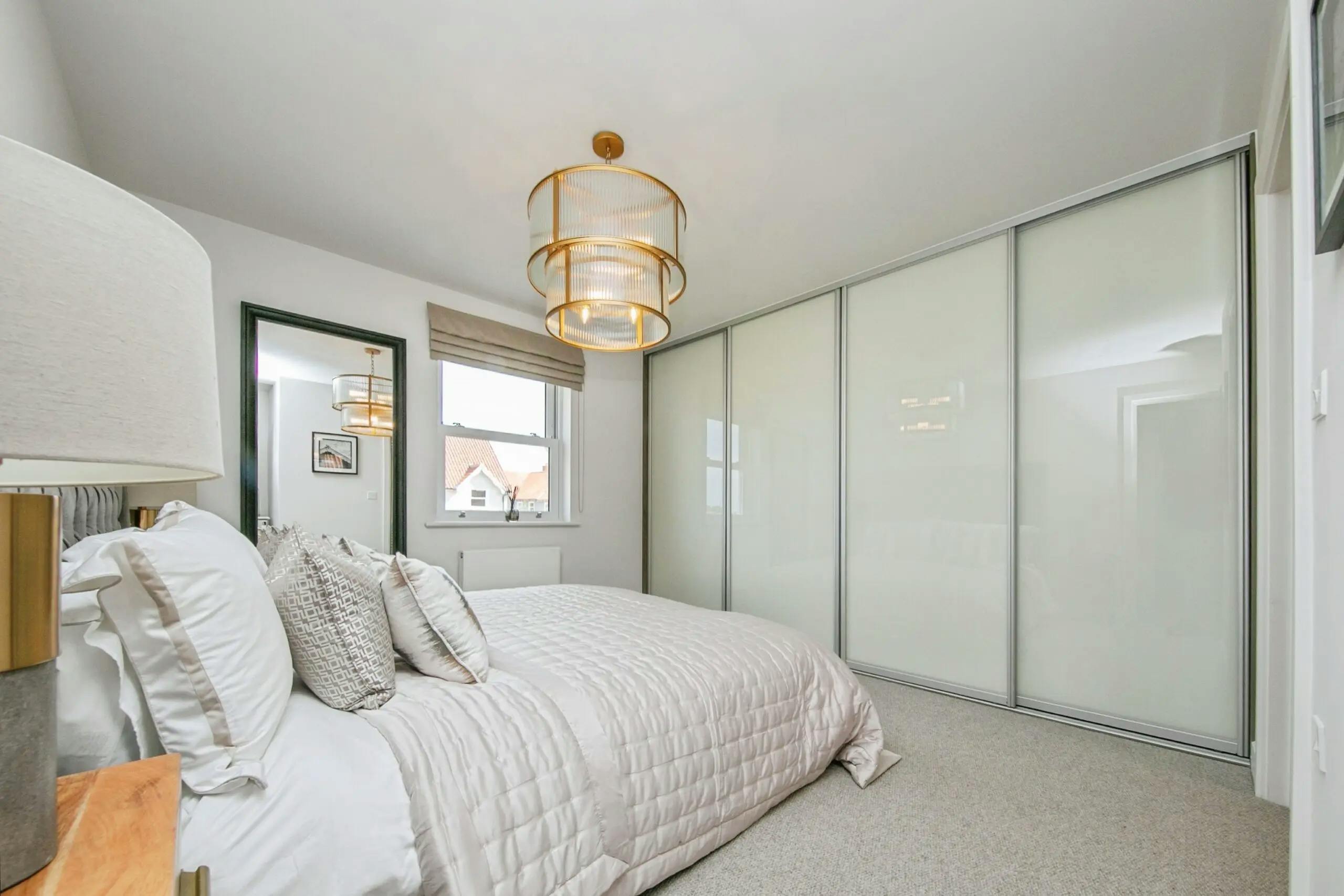 Caption: a bedroom with a white bed and white closets