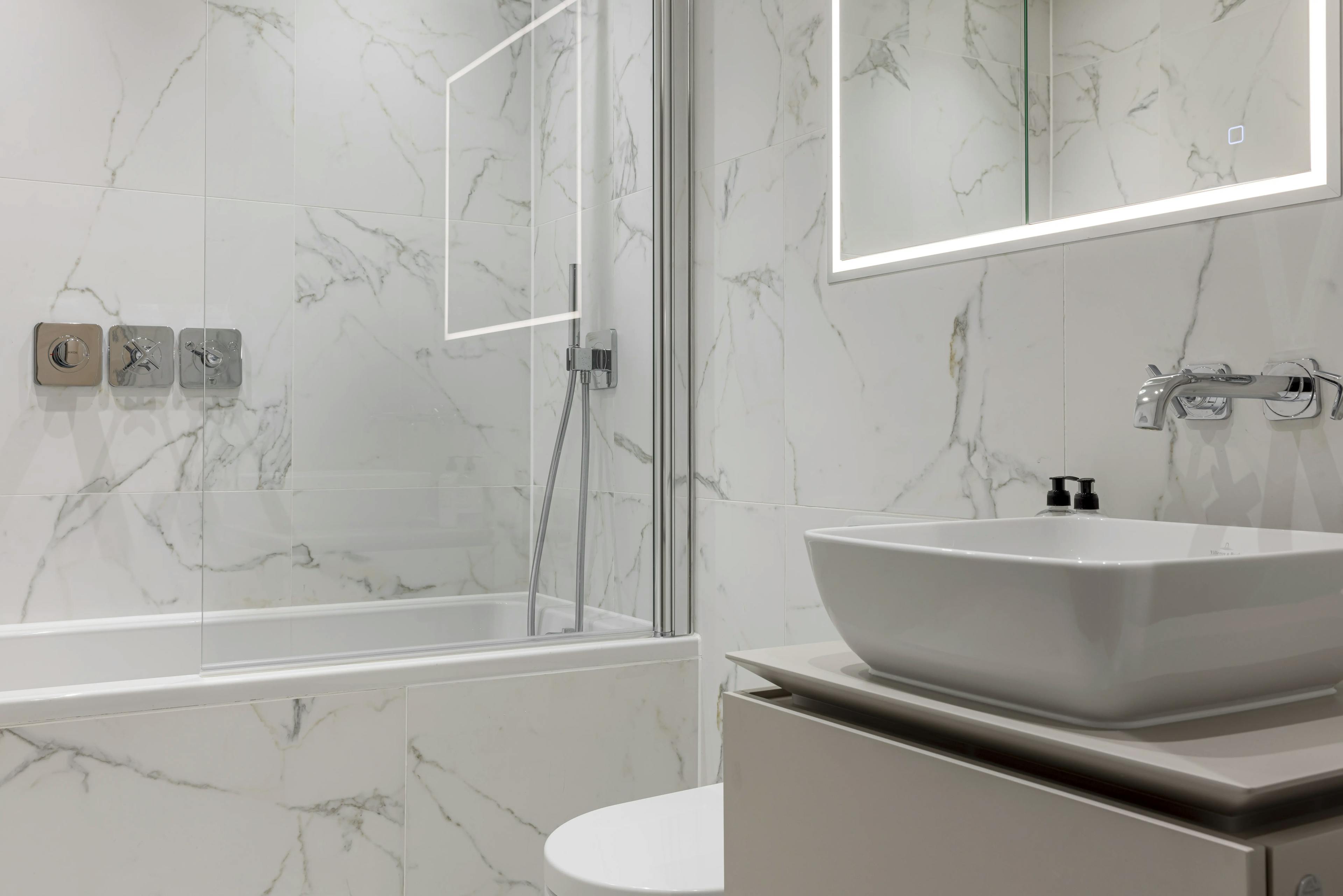 Caption: a bathroom with a sink, mirror, and bathtub