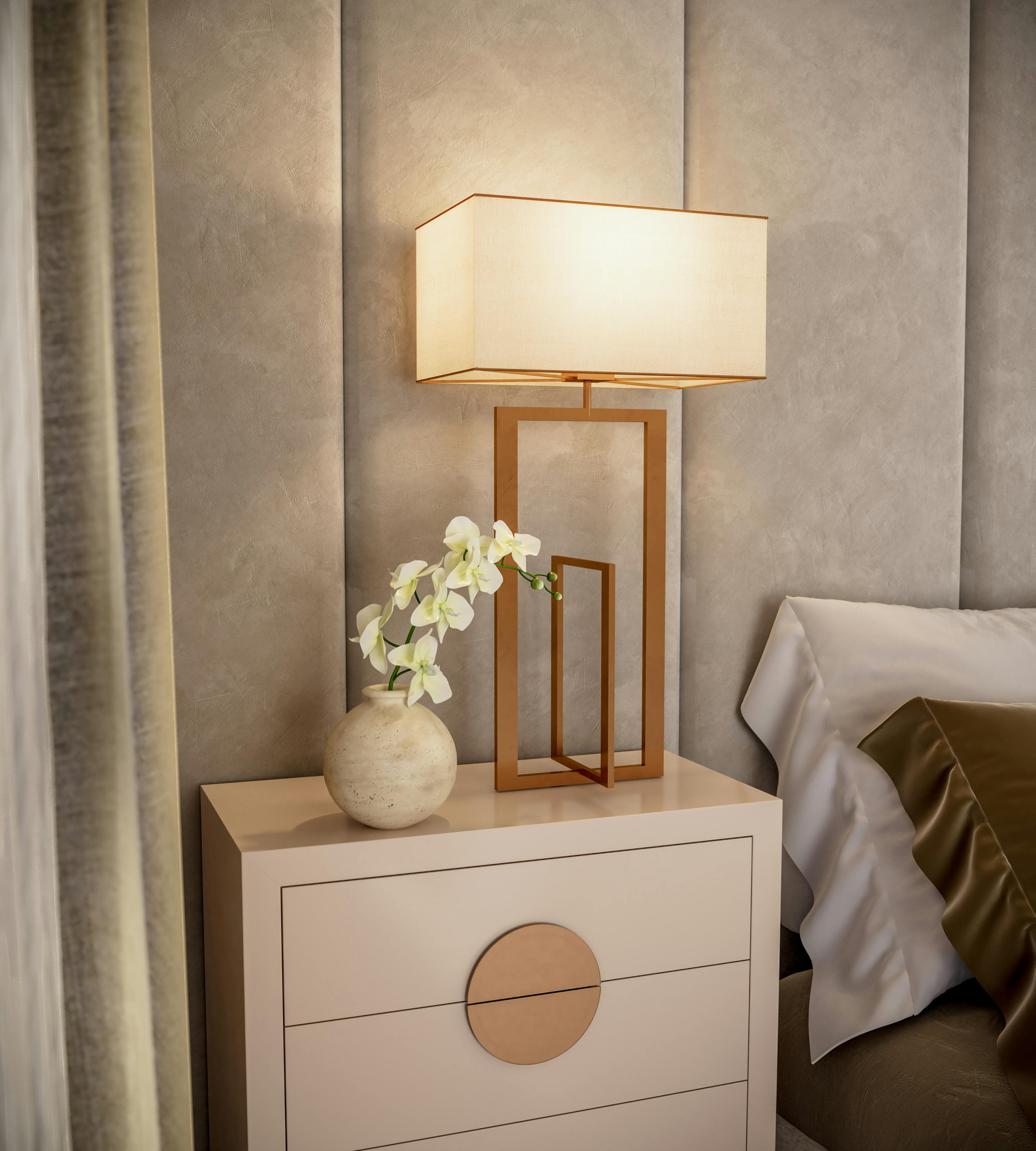 Caption: a nightstand with a lamp and a vase with flowers on it