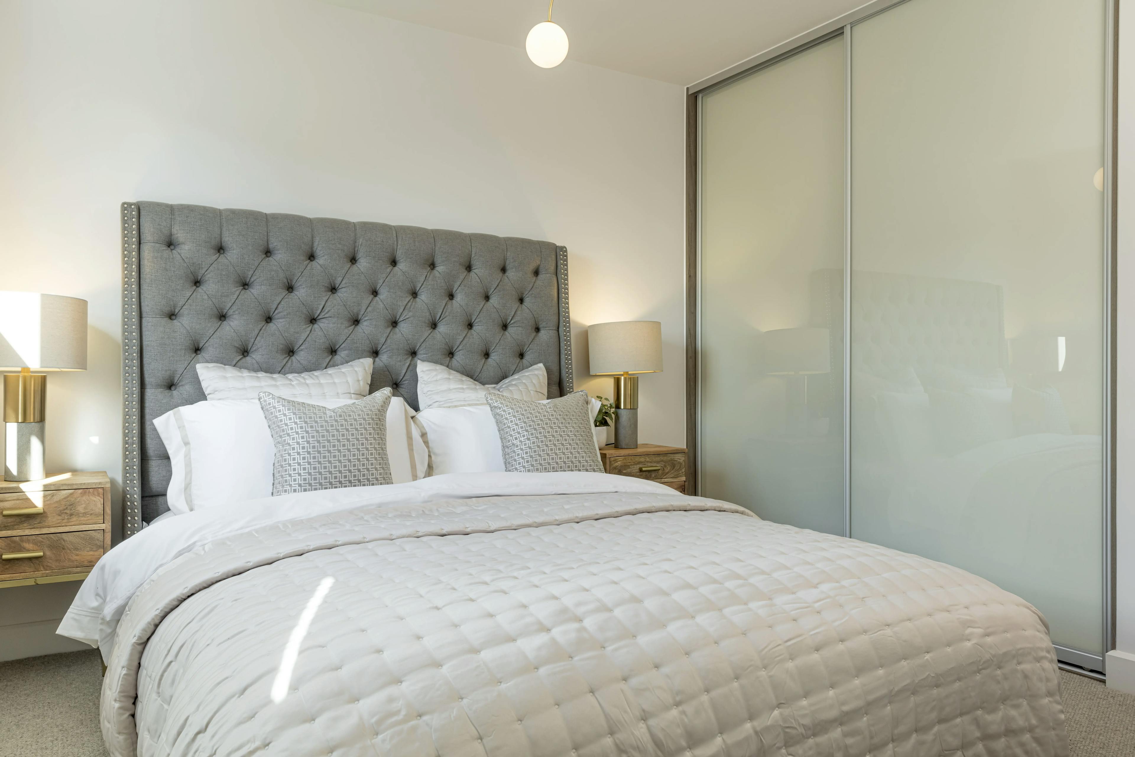 Caption: a bedroom with a bed, nightstands, and a closet