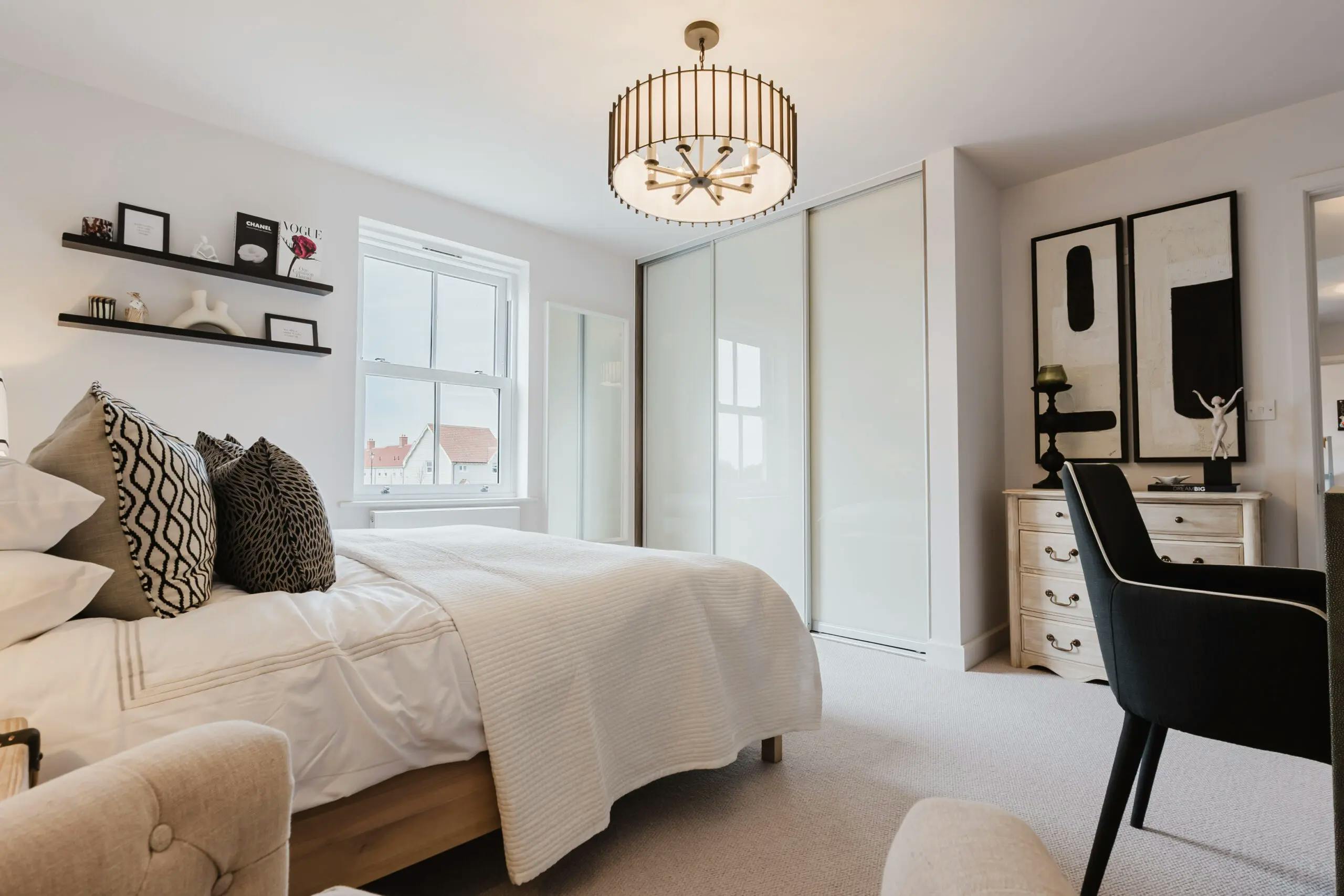 Caption: a bedroom with a bed, chair, desk and a window