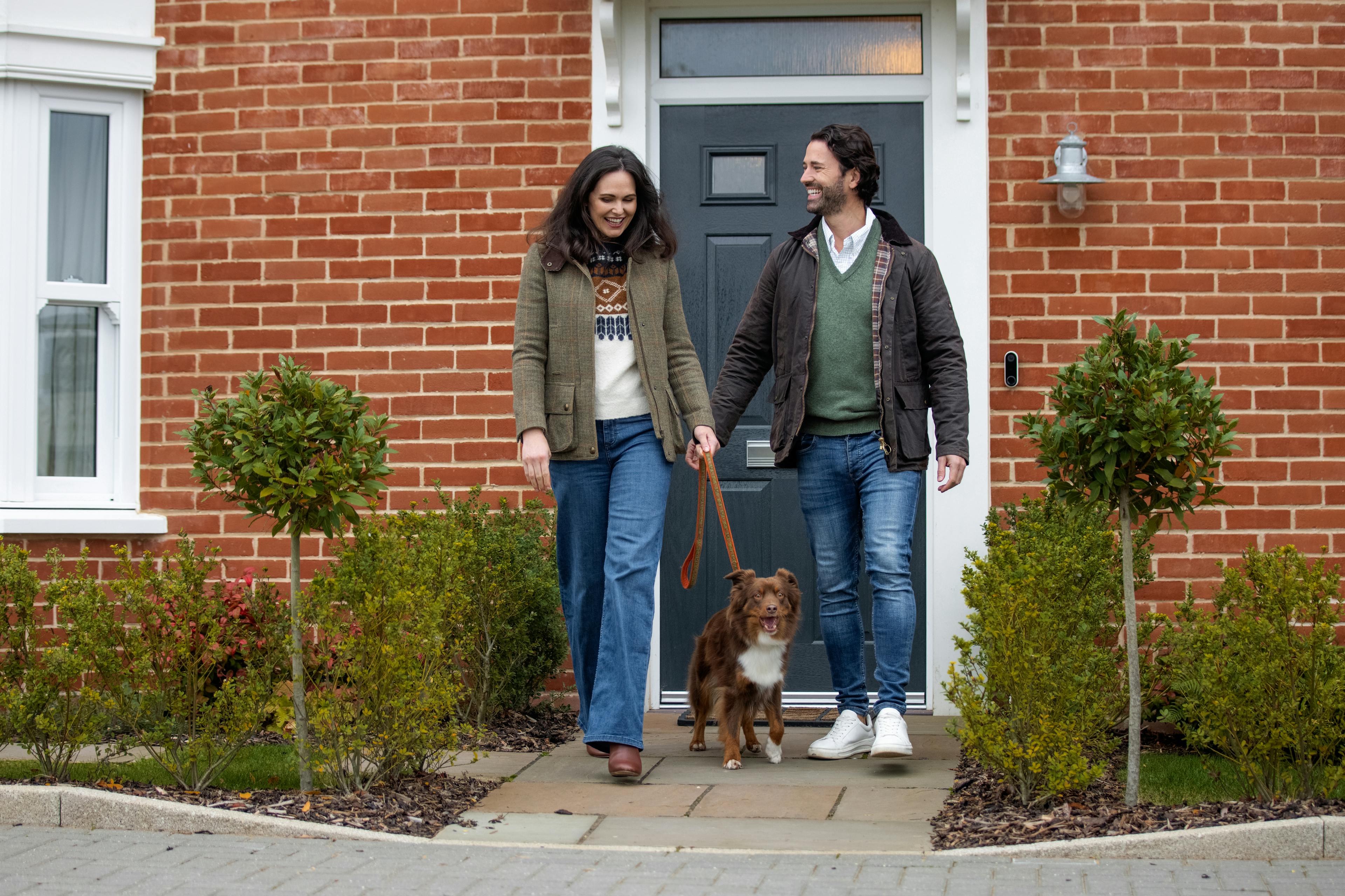 Caption: a man and a woman walking a dog on a leash