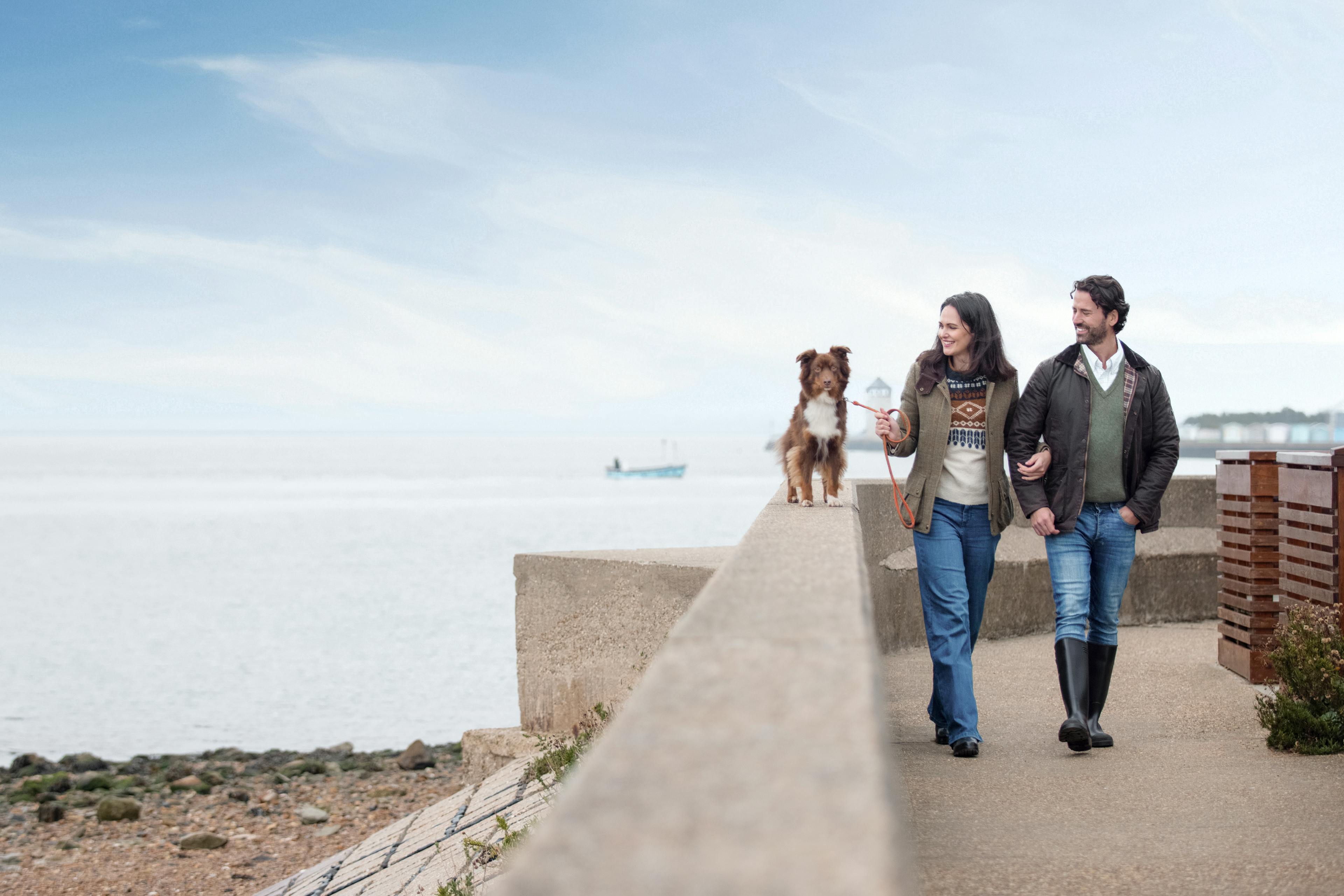 Caption: a man and a woman walking down a sidewalk next to a dog
