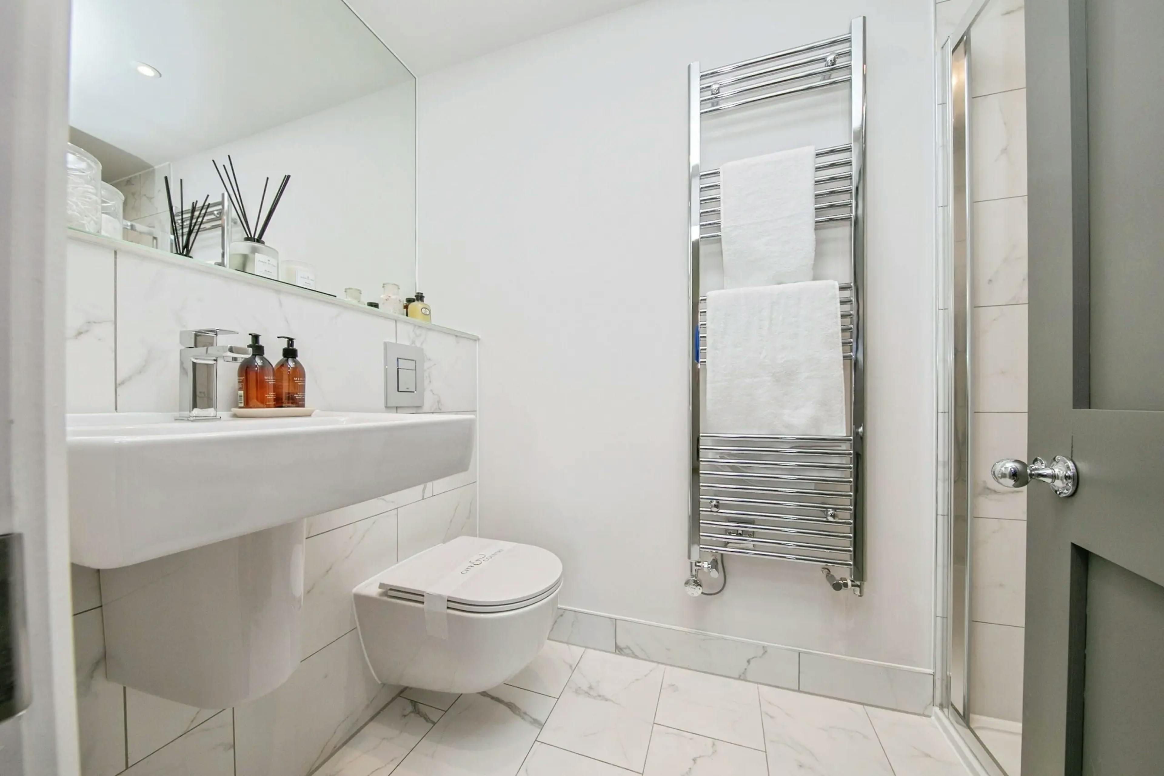 Caption: a bathroom with a toilet, sink, and towel rack