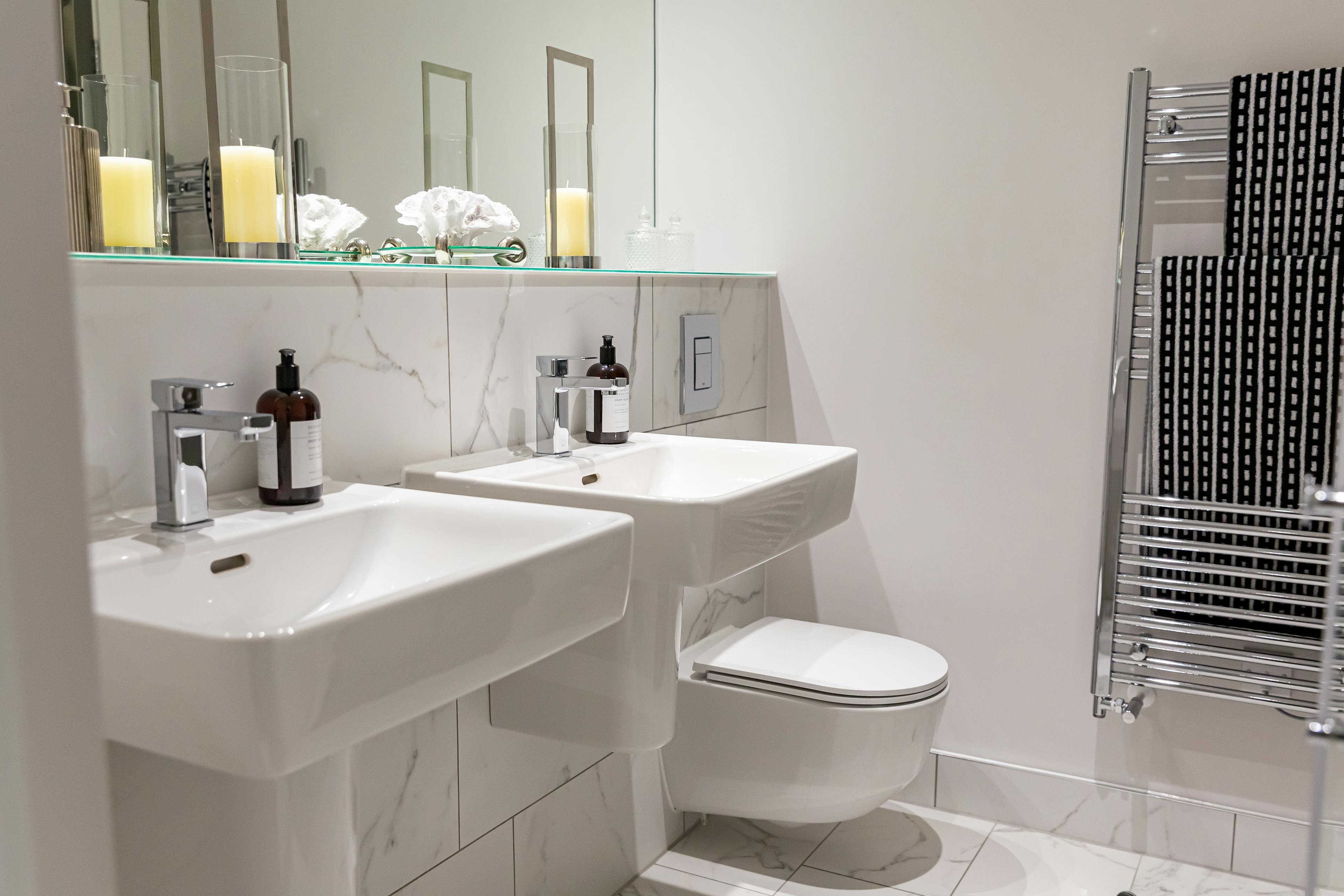 Caption: a bathroom with two sinks, a toilet and a radiator