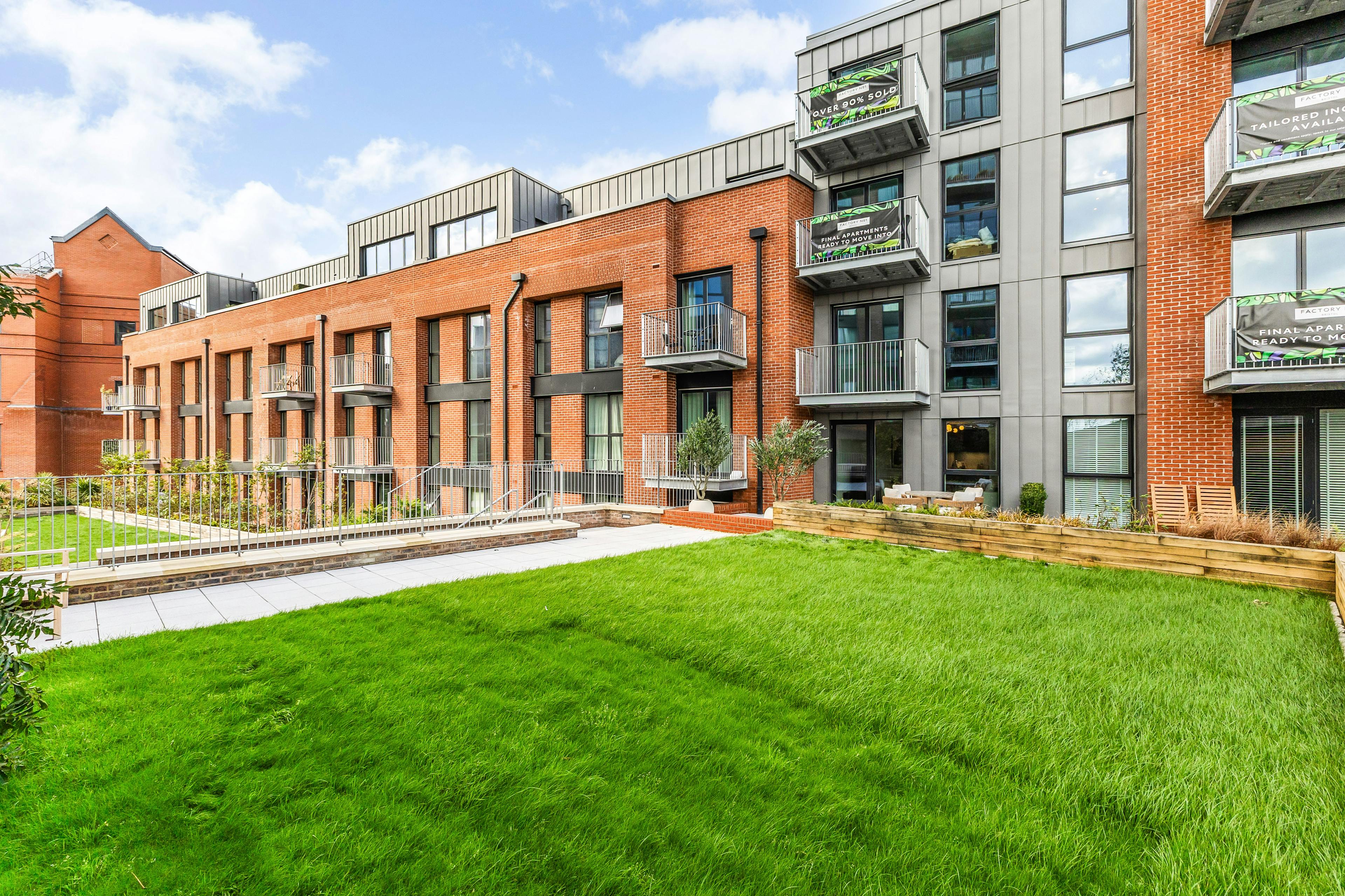 Caption: a green lawn in front of a brick building