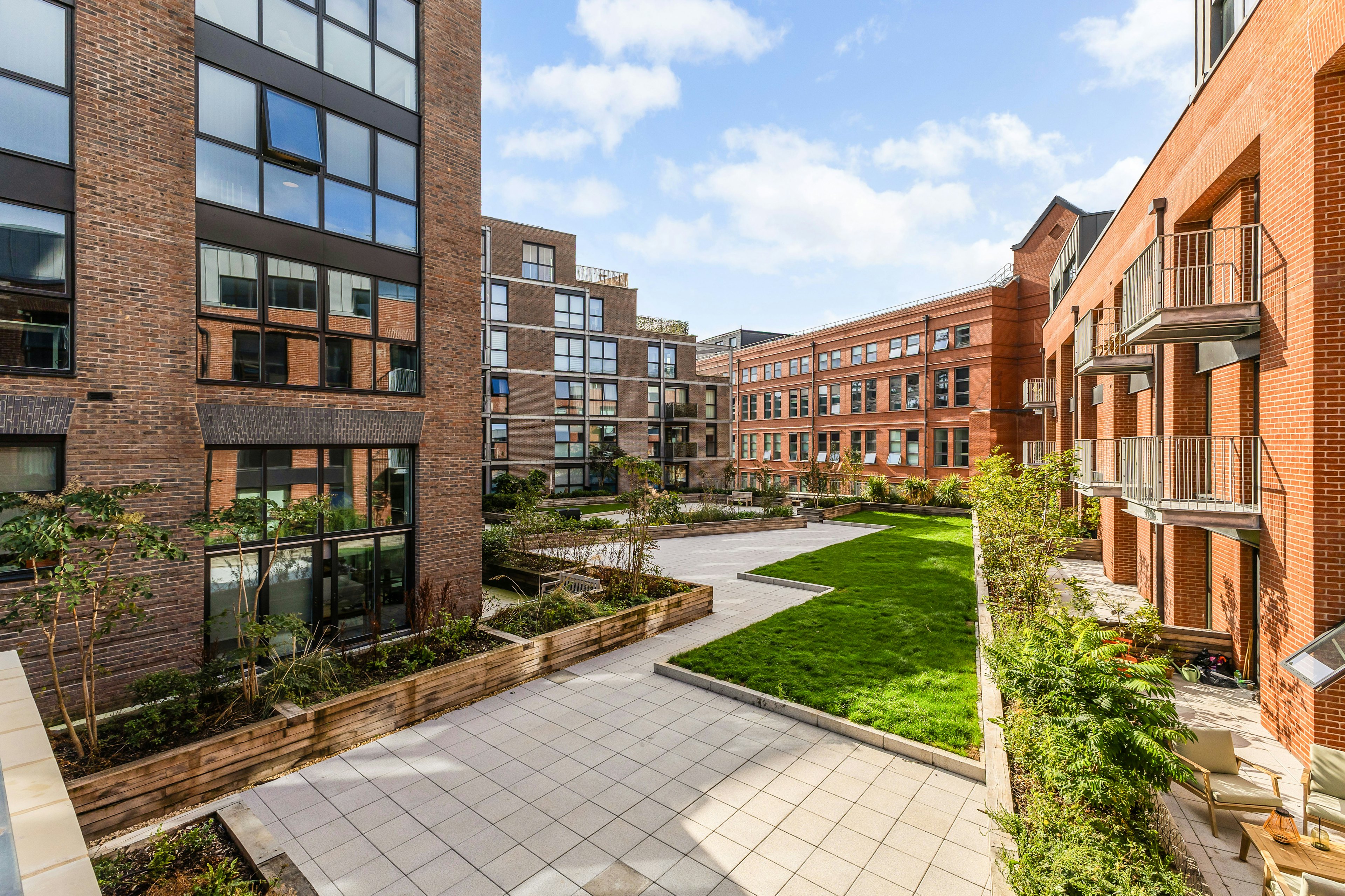 Caption: a courtyard in a brick building with a green lawn