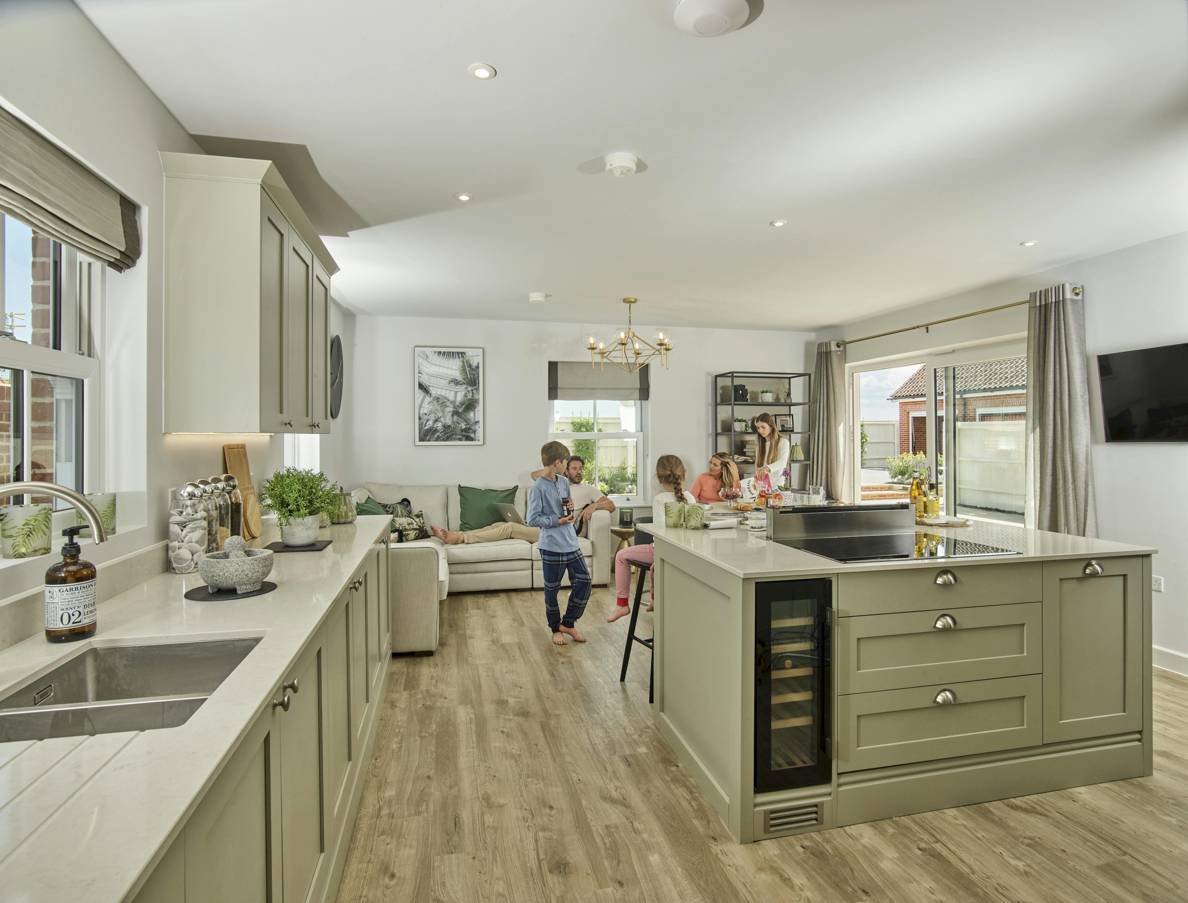 Caption: a couple of people standing in a kitchen next to a living room