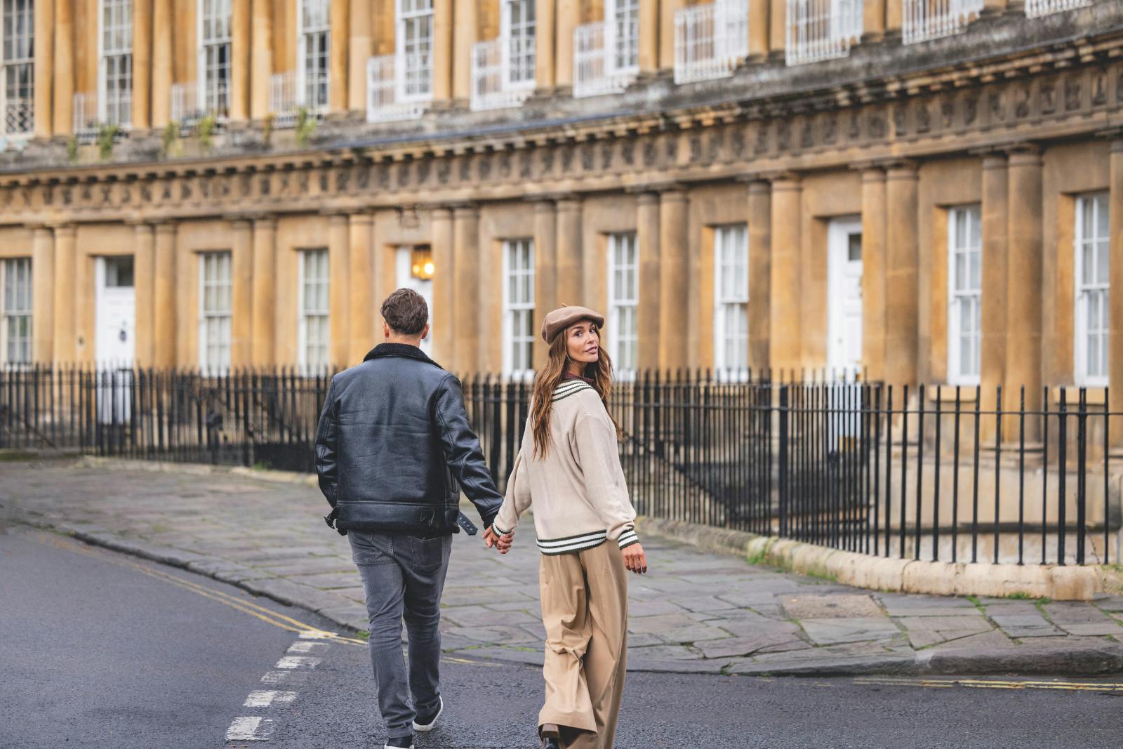 Caption: a man and a woman walking down a street holding hands