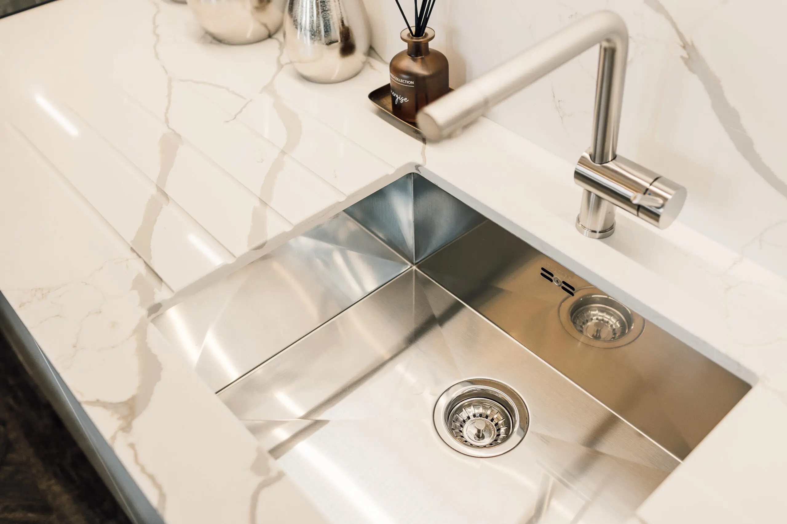 Caption: a kitchen sink with a chrome faucet and a marble counter top