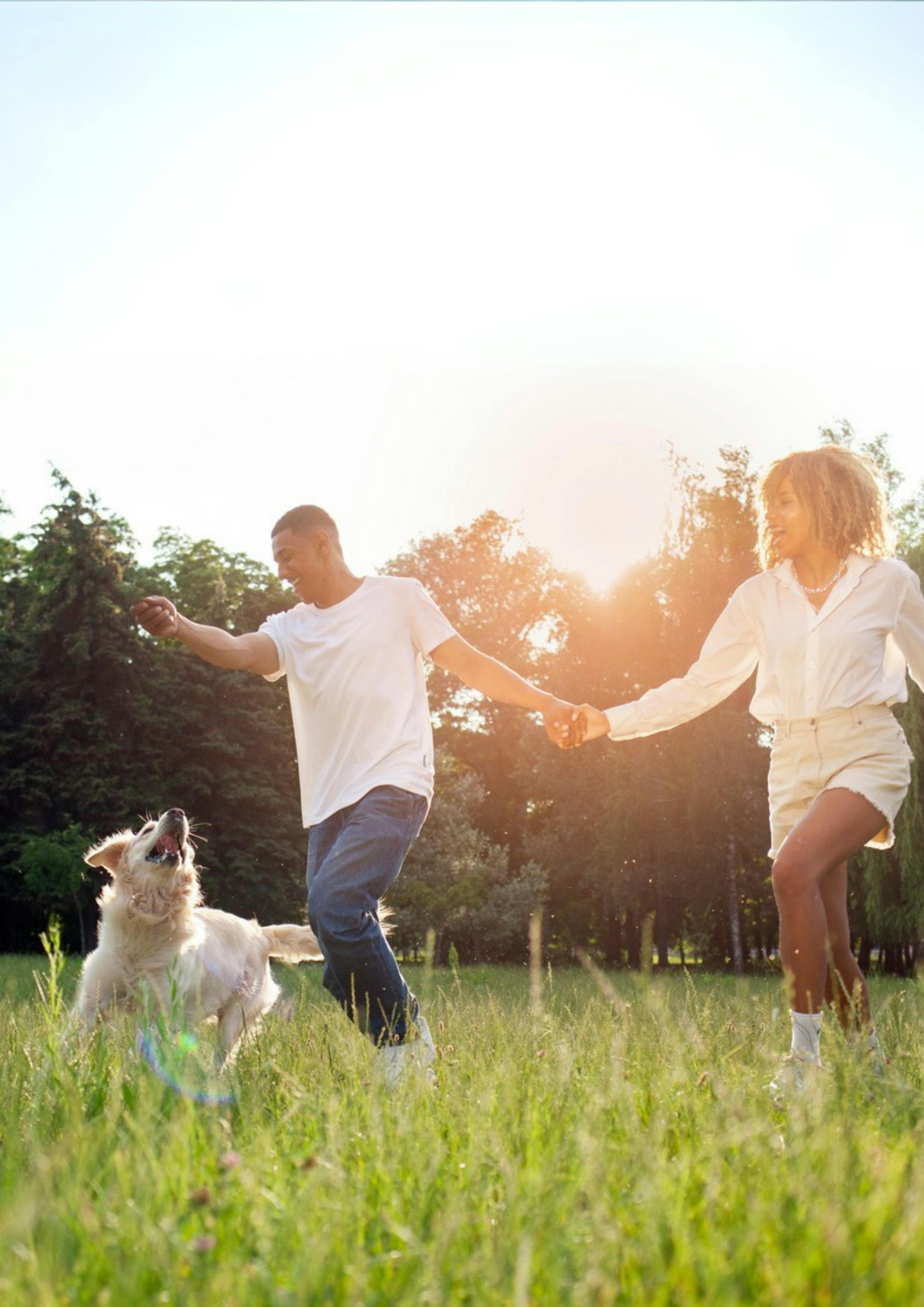 Caption: a man and a woman holding hands and a dog running in a field