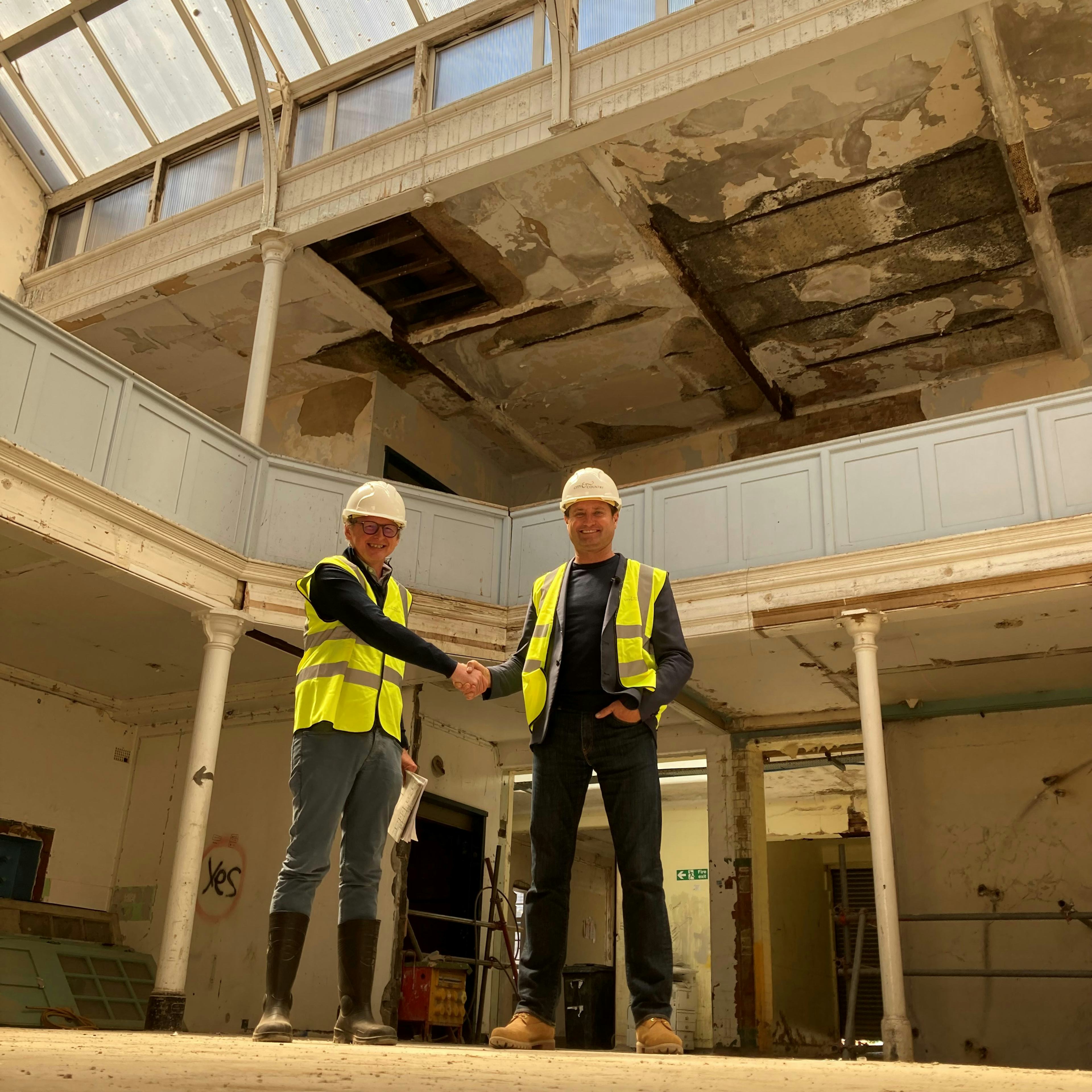 Caption: two construction workers shaking hands in a building