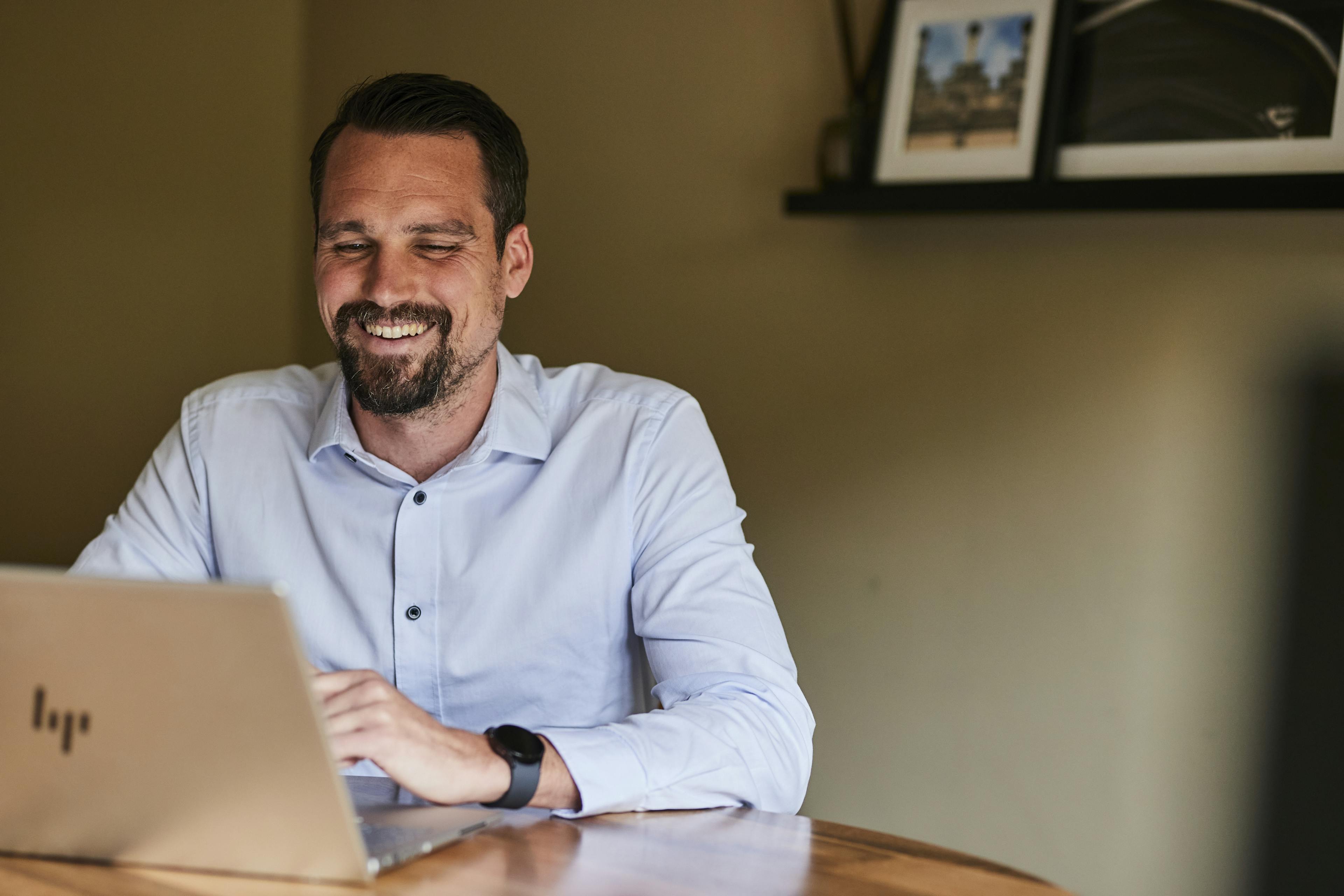Caption: a man sitting at a table with a laptop