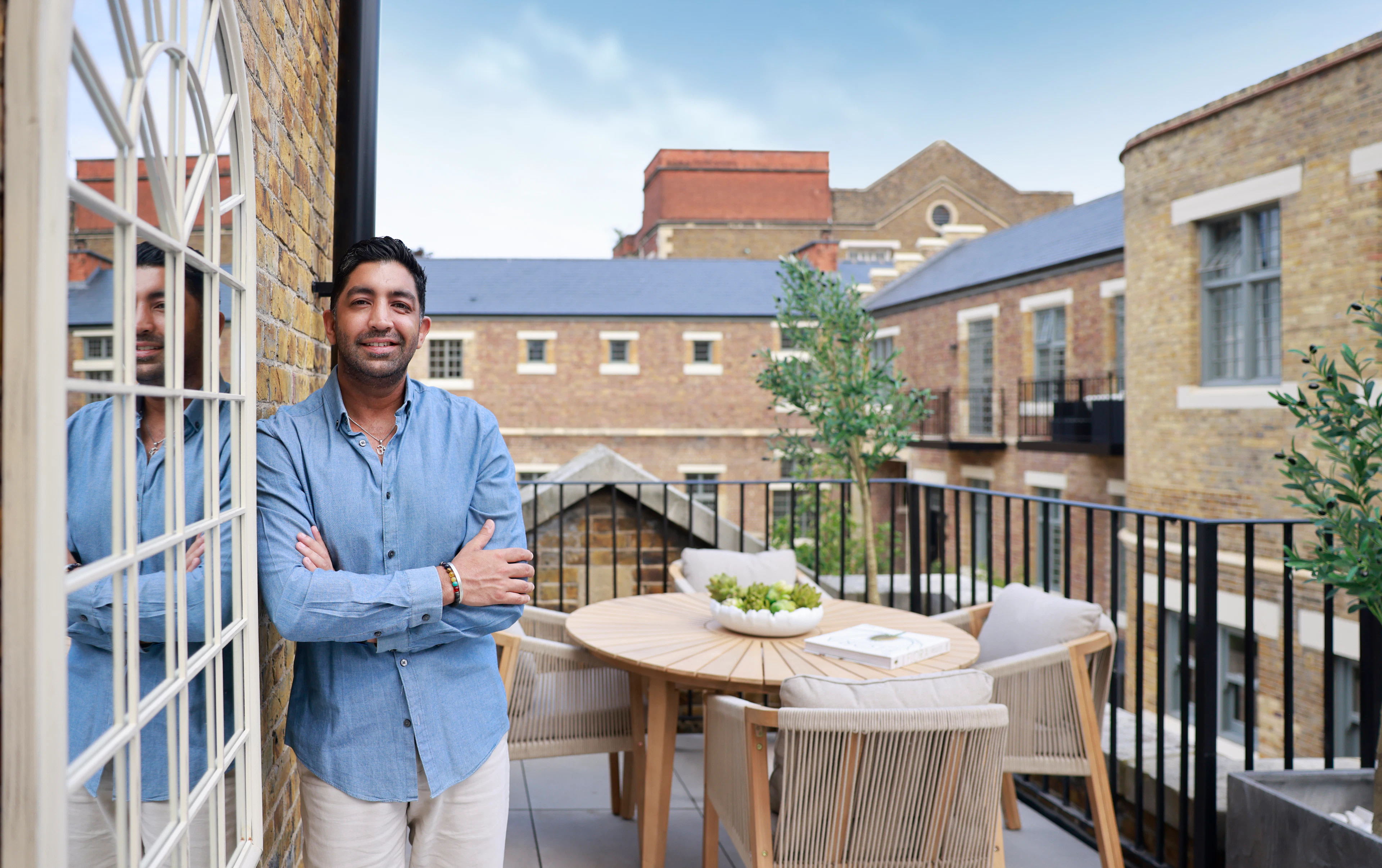Caption: a man standing on a balcony next to a table