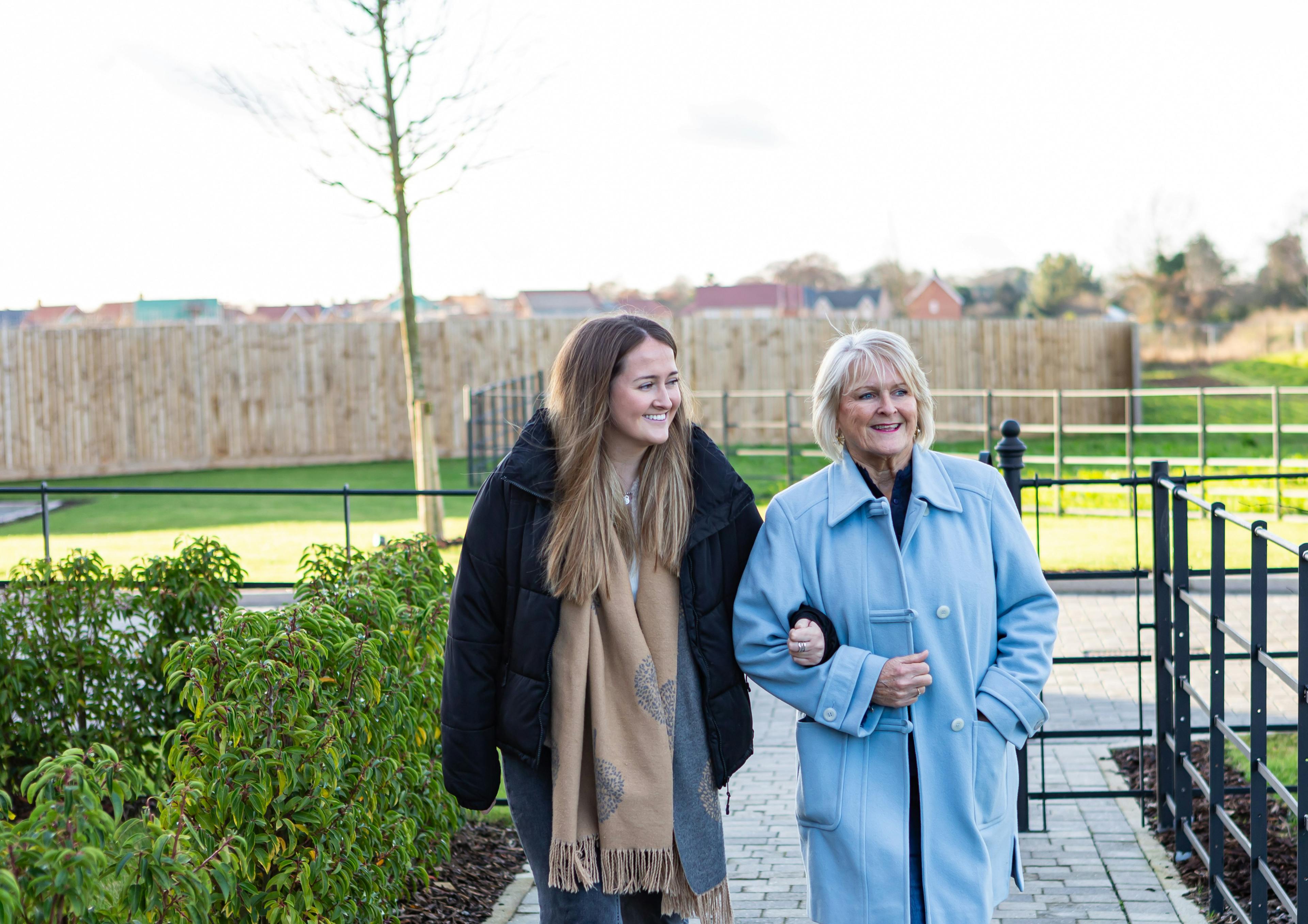 Caption: a couple of women walking down a sidewalk