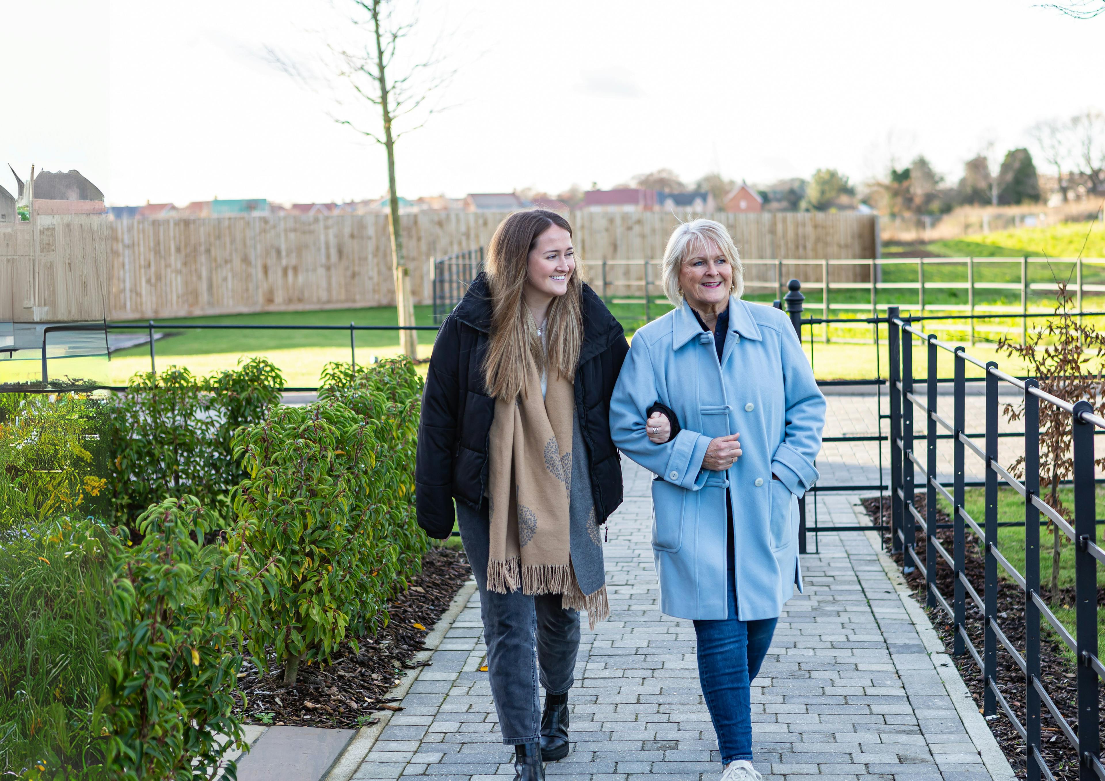 Caption: a couple of women walking down a sidewalk
