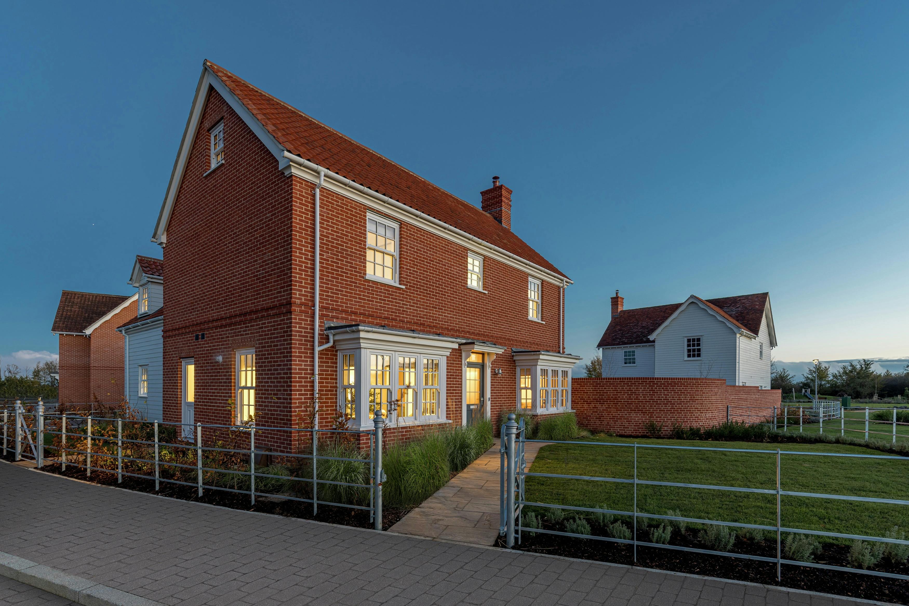 Caption: a red brick house with a fence around it